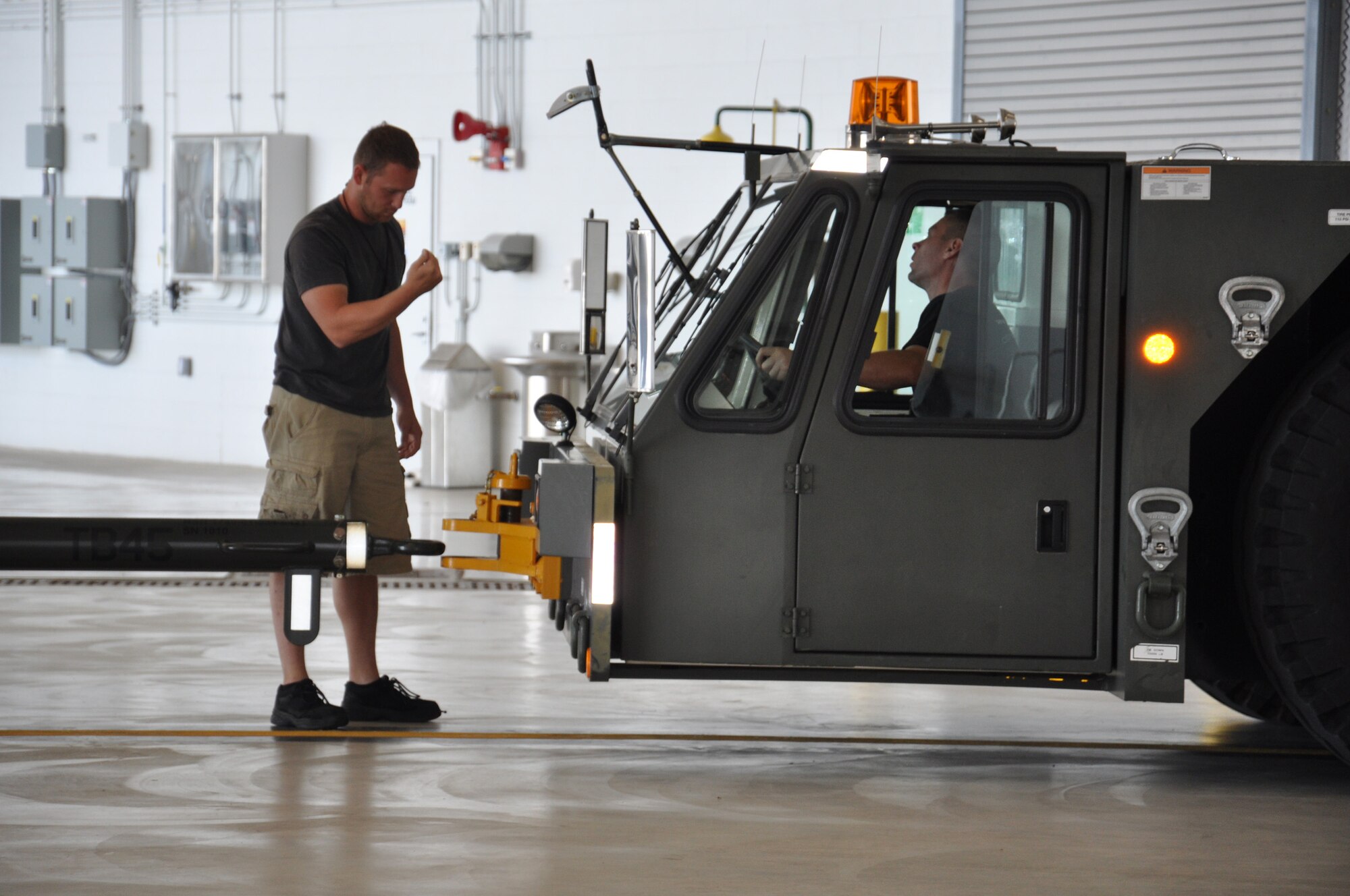WRIGHT-PATTERSON AIR FORCE BASE, Ohio – Tech. Sgt. Stephen Billingsley, tow supervisor, directs Staff Sgt. Bill Burdick where to stop while preparing to hook up then tow a  445th Airlift Wing C-17 Globemaster III out of the hangar June 29.  Both are assigned to the 445th Aircraft Maintenance Squadron. (U.S. Air Force photo/Stacy Vaughn)