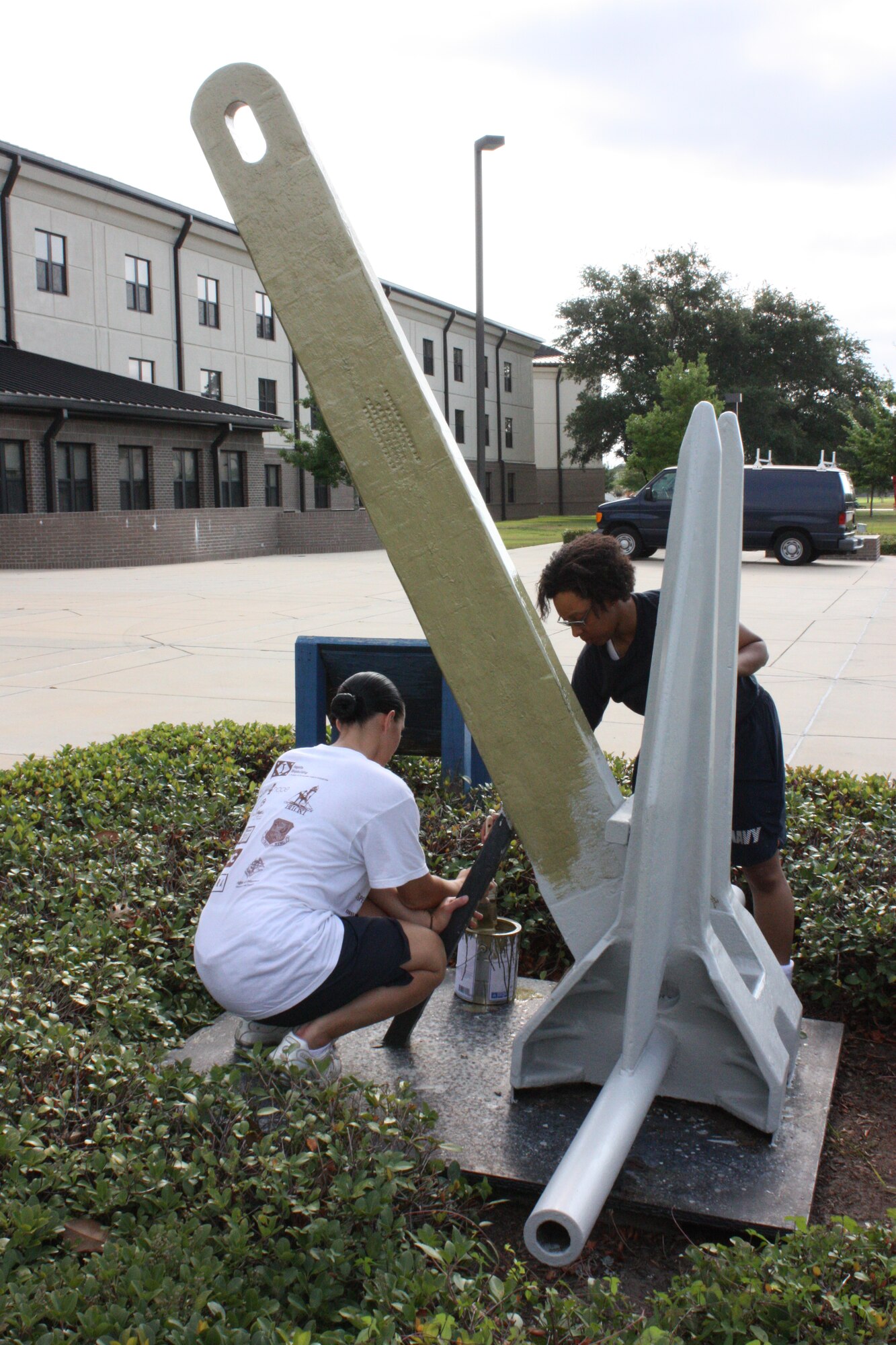 Keesler Center for Naval Aviation Technical Training Unit Airman Carolyn Jones and Airman Apprentice Tabitha Hernandez paint the anchor in front of Alho Manor gold, a
symbol of distinction practiced by deployable ships for earning the Retention Excellence Award, also known as the Golden Anchor Award. It’s given by the Department of the Navy for sustaining superior levels of military retention.  (Photo by Aviation Electronics Technician 2nd Class Raymond Lee)