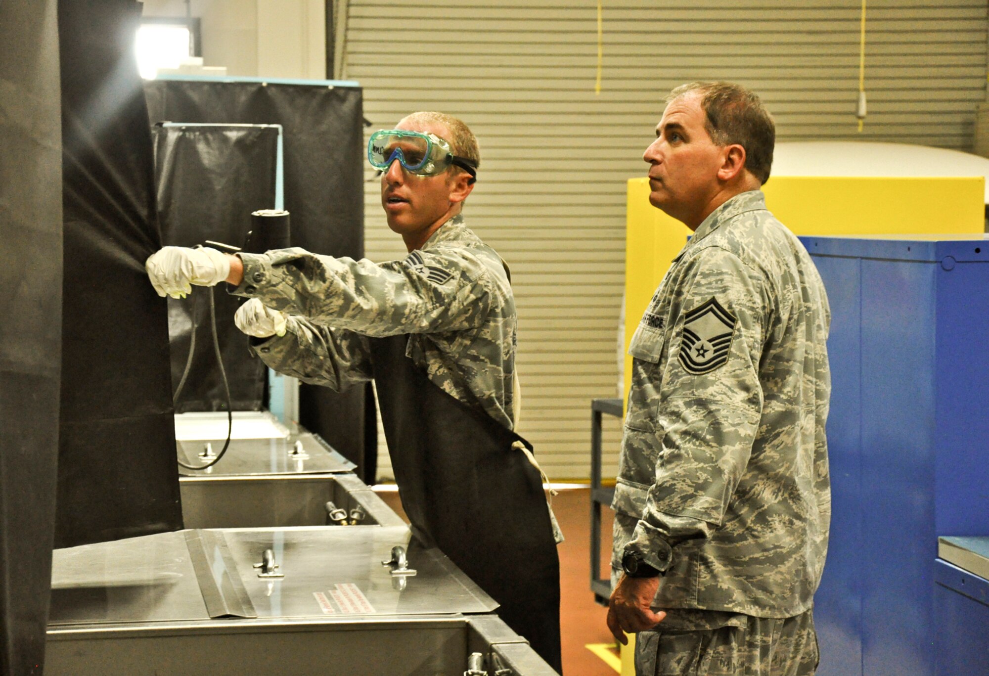 Senior Airman Bradley Levander Jr. explains to his father, Senior Master Sergeant Bradley Levander Sr.,  how part demagnification works at his work station on June 22, 2011 at Joint Base Charleston, S.C. (U.S. Air Force Photo/SSgt. Rashard Coaxum)