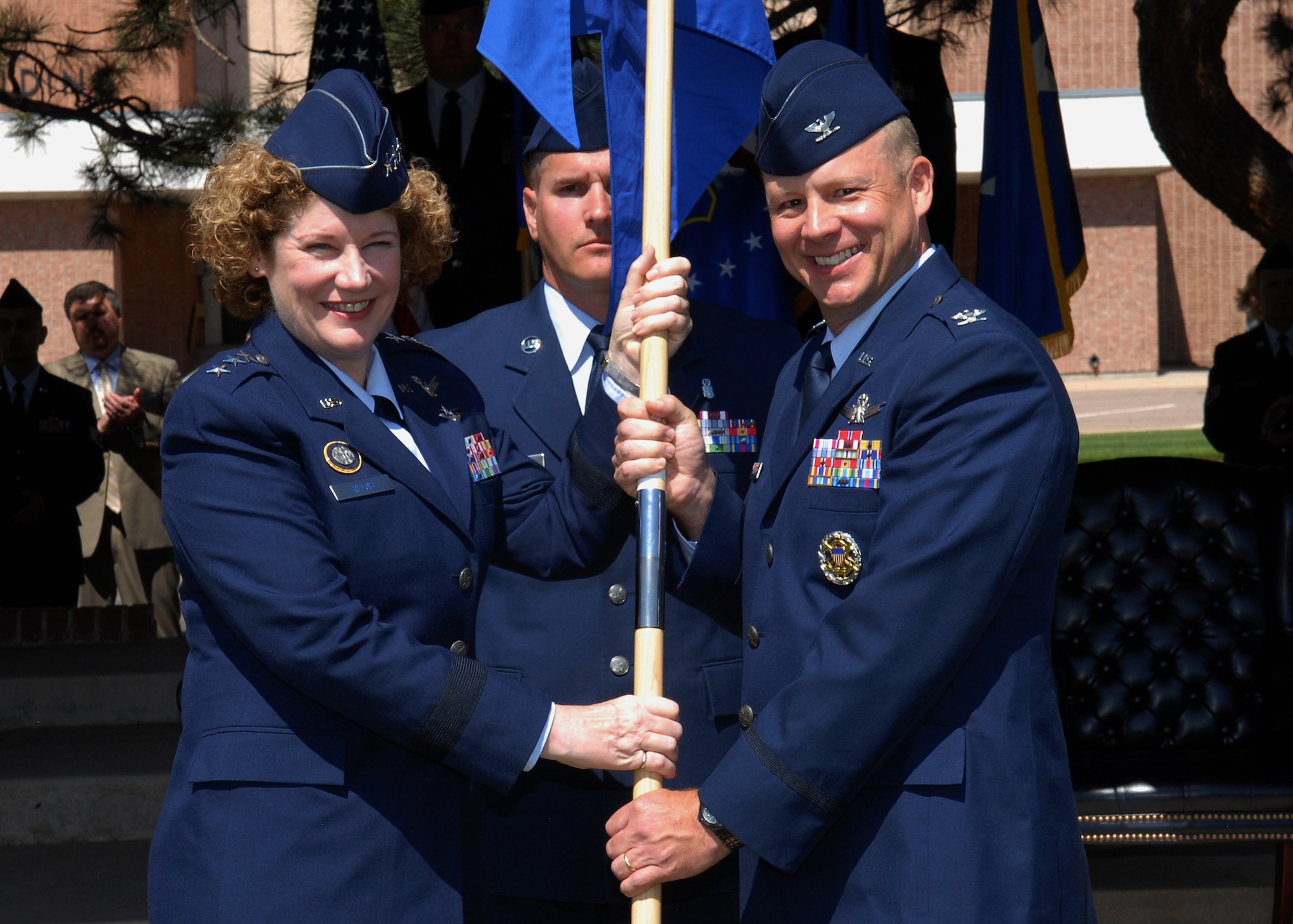 Lt. Gen. Susan Helms (left), 14th Air Force commander, passes the 21st Space Wing guidon to Col. Chris Crawford, 21st Space Wing commander, during a change of command ceremony June 28 on the Peterson Air Force Base parade field. Colonel Crawford assumed command from Col. Stephen N. Whiting during the time-honored ceremony. (U.S. Air Force photo/Rob Bussard)