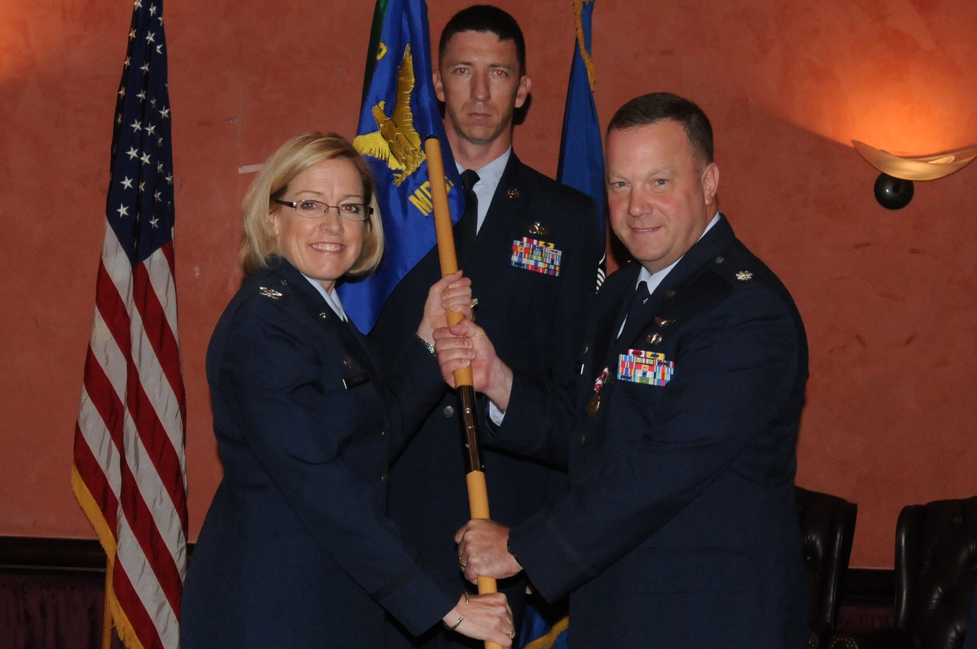 Lt. Col. Scott B. Holliday passes the 31st Medical Operations Squadron guidon to Col. Linda L. Lawrence, 31st Medical Group commander, during the 31st MDOS change of command ceremony June 24 at Aviano Air Base, Italy. Colonel Holliday relinquished command to Lt. Col. Guy R. Majkowski and will head to Ramstein Air Base, Germany, to work in aerospace physiology.(U.S. Air Force photo/Airman LaVel Sterling)