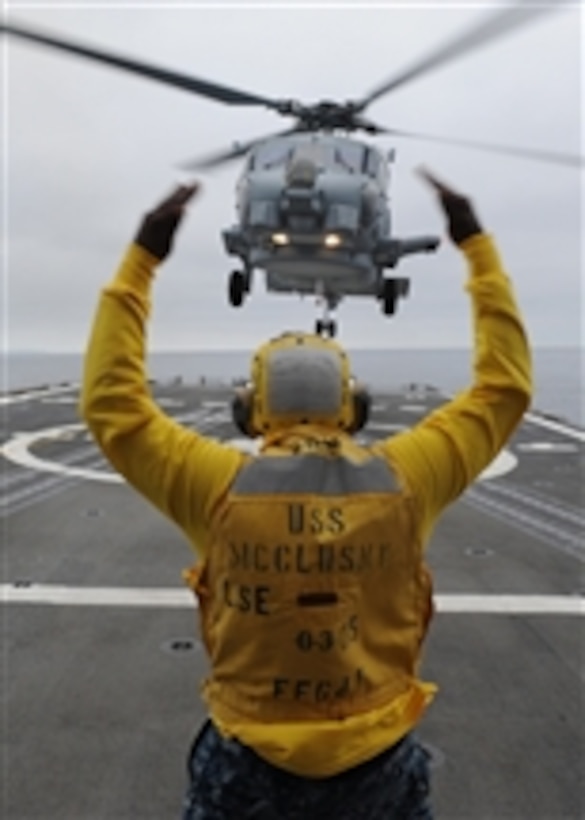 Petty Officer 3rd Class Lazarus Bullock, enlisted landing signalman aboard the guided-missile frigate USS McClusky (FFG 41), guides an SH-60R Sea Hawk helicopter onto the flight deck during deck landing qualifications while the ship is underway in the Pacific Ocean on June 24, 2011.  