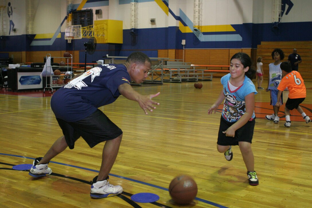 Vinesys RodriguezSegarra, 9, performs a crossover against Sean E. Oakry, a summer camp coach, as part of crossover drills during the Marine Corps Community Services Iwakuni Commands Summer Camp at the IronWorks sports courts here June 28. RodriguezSegarra was one of several children who took part in the basketball segment of the camp which lasted from June 27-29. Dodgeball was the next camp that was offered at the conclusion of the basketball camp. It lasted from June 30-July 1.