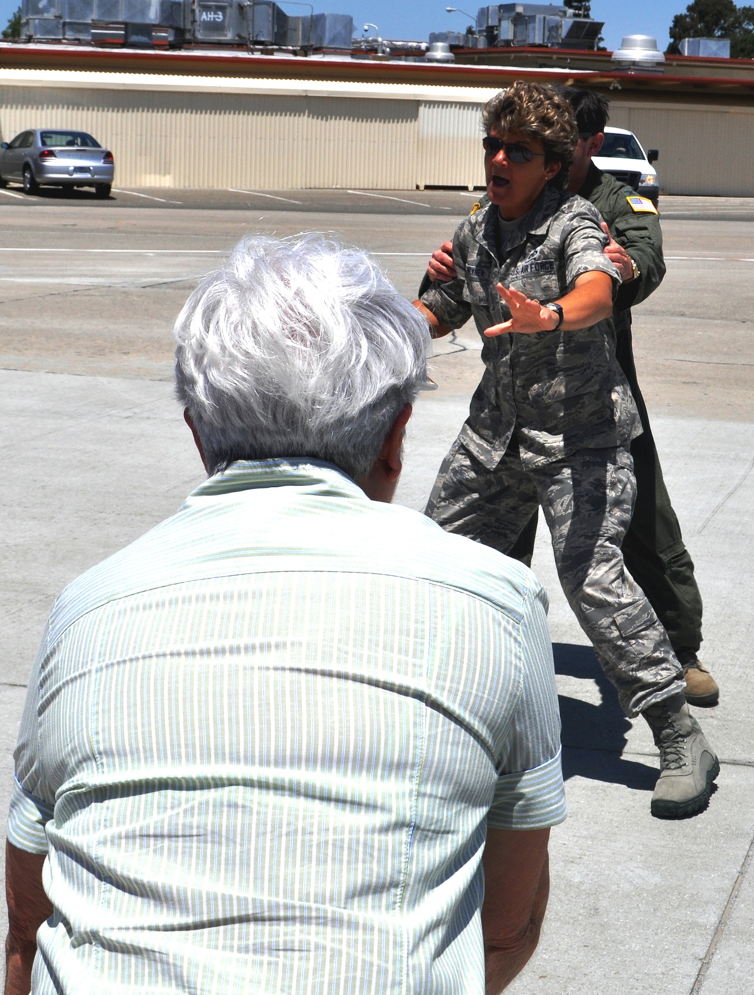 TRAVIS AIR FORCE BASE, Calif. -- Col. Barrett Broussard hides behind Chief Master Sgt. Kathleen Buckner as his mother Lorraine, takes aim with her water canister. The colonel celebrated his "fini" flight in a Travis AFB C-17, and was met on the flight line by about 50 Airmen, family and friends, waiting to hose him down. (U.S. Air Force photo/Senior Master Sgt. Ellen L. Hatfield)