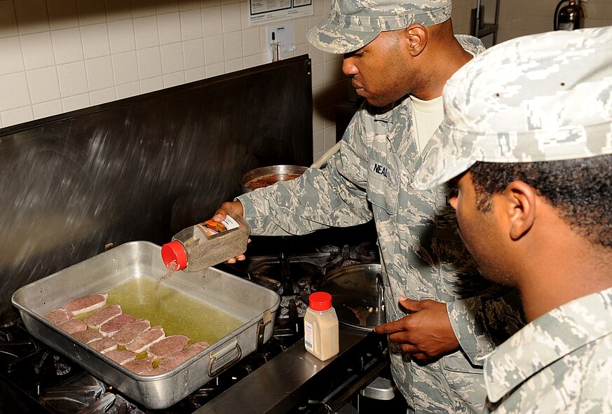 Staff Sgt. Deon Neal, 2nd Force Support Squadron, mentors an airman on how to season steaks in the Red River Dining Facility on Barksdale Air Force Base, La., June 29. It is important for food service personnel to understand proper seasoning portions so the food is not over seasoned. (U.S. Air Force photo/Senior Airman Kristin High)(RELEASED)