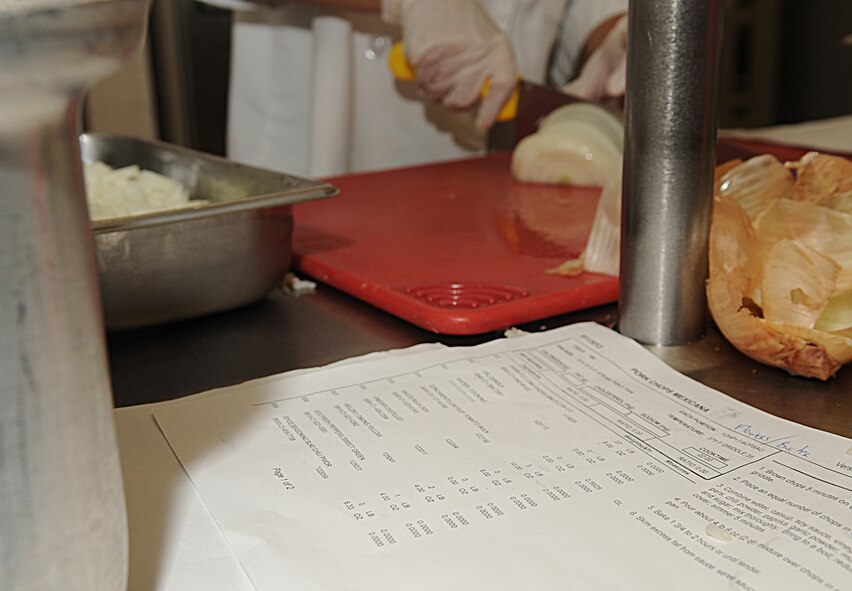 A recipe for Spanish rice sits next to Senior Airman Michele Delvecchio, 2nd Force Support Squadron, as she chops onions in the Red River Dining Facility on Barksdale Air Force Base, La., Jun 29. Airmen are required to follow all recipes to ensure the proper ingredients and amount are being used. (U.S. Air Force photo/Senior Airman Kristin High)(RELEASED)