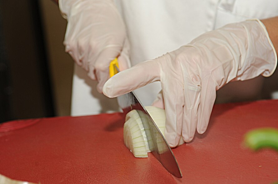 Senior Airman Michele Delvecchio, 2nd Force Support Squadron, chops onions in the Red River Dining Facility on Barksdale Air Force Base, La., June 29. Airman Delvecchio used the onions for a Spanish rice recipe to be served during lunch. (U.S. Air Force photo/Senior Airman Kristin High)(RELEASED)