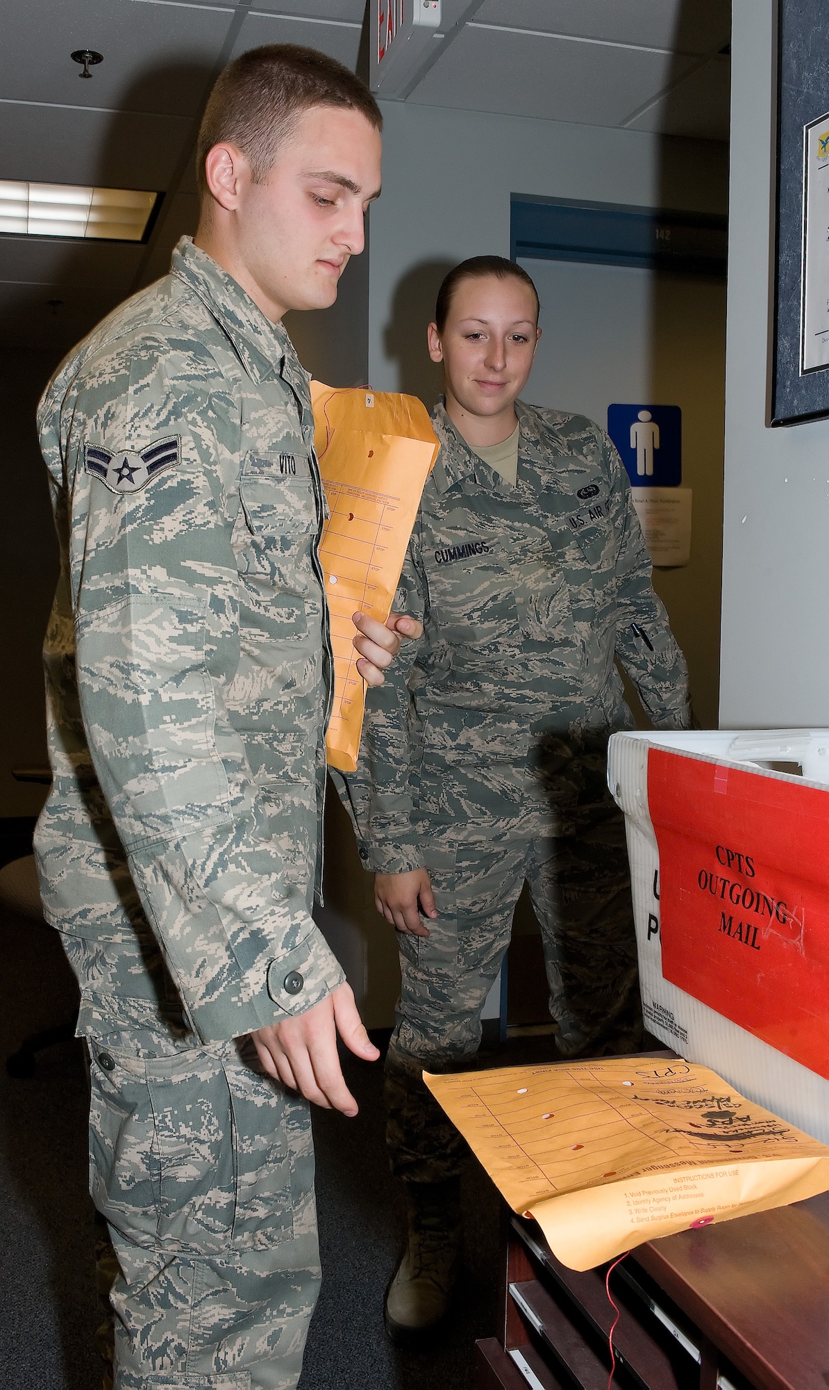 Airman 1st Class Michael Vito (left) and A1C Caroline Cummings, 436th Communications Squadron knowledge operations managers, deliver mail June 30, 2011, at Dover Air Force Base, Del. The Airmen deliver mail to almost every agency on base. (U.S. Air Force photo by Airman 1st Class Samuel Taylor)