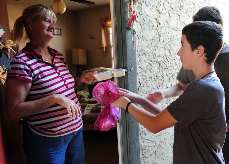 DYESS AIR FORCE BASE, Texas – Donna Dules, a Meals-on-Wheels recipient, is hand-delivered her ready-made meal from Luke Schroeder, 11, son of Tech. Sgt. James Schroeder, 7th Mission Operations Squadron, in the local Abilene community June 30, 2011. Children ages 9-18 from the youth center here perform a Meals-on-Wheels route every Thursday morning in the city of Abilene. (U.S. Air Force photo by Senior Airman Chelsea Browning/Released)