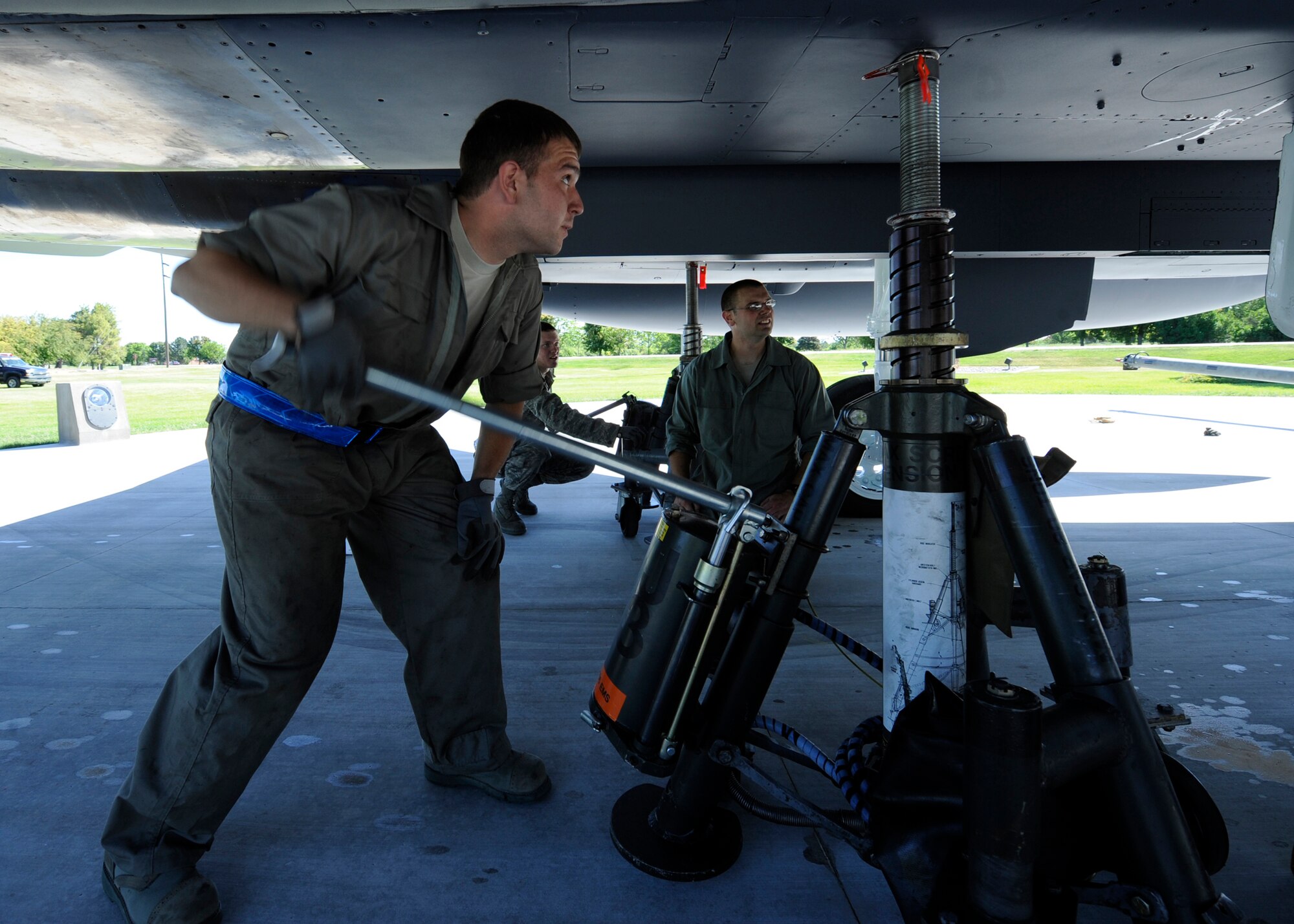 MOUNTAIN HOME AIR FORCE BASE, Idaho – Airman 1st Class Mike Couch, 366th Equipment Maintenance Squadron, pumps 1 of 3 jacks used to raise the newly positioned F-15E Strike Eagle aircraft static display here June 25. Tech Sgt. Darin Sanders, 366th Equipment Maintenance Squadron, watches Airman Couch’s progress as well as the aircraft’s positioning in order to minimize the possibility of damage and injury. (U.S. Air Force photo by Senior Airman Angelina Drake)