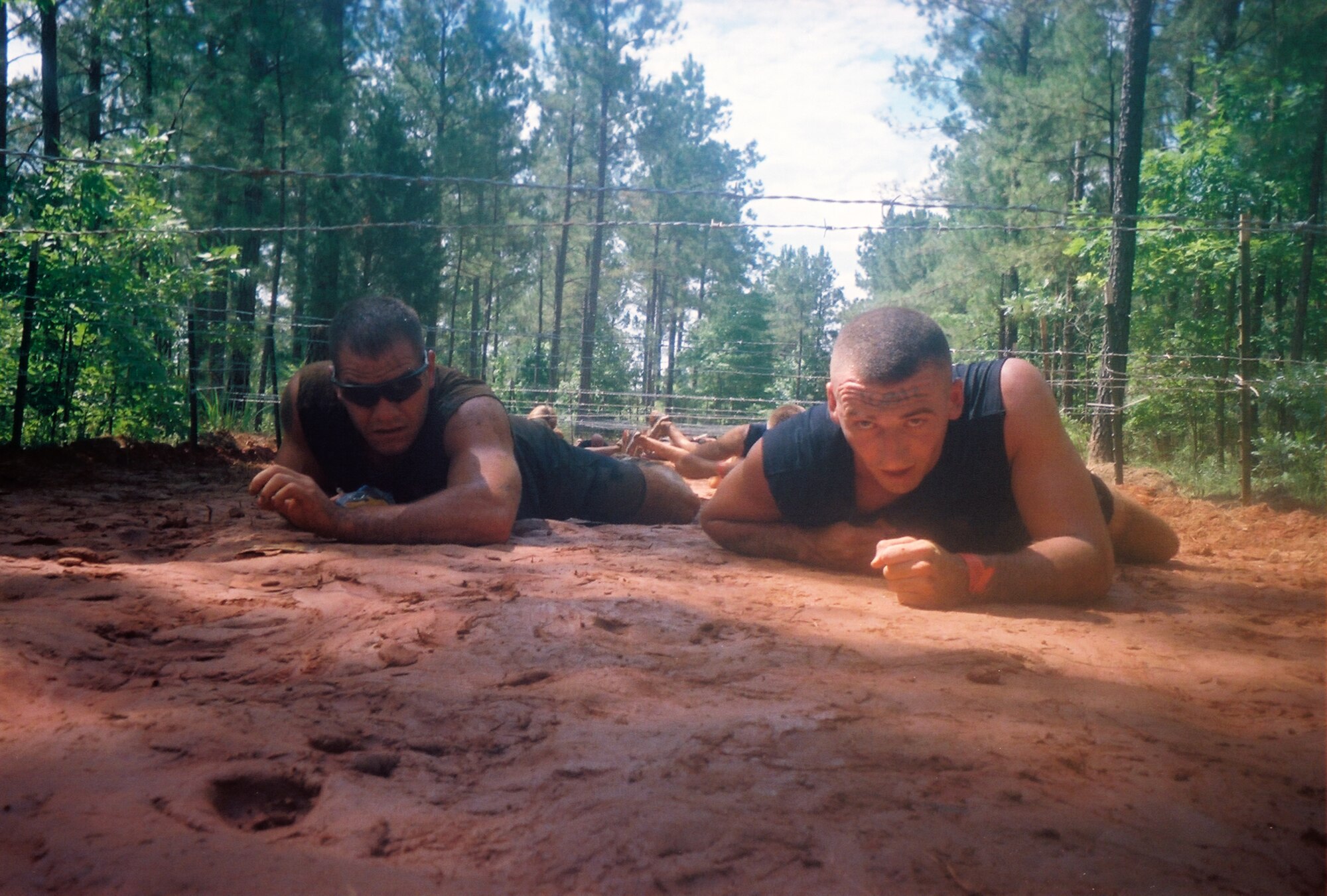 WINNSBORO, S.C. - Senior Airman John Makripodis (left) and Staff Sgt. James Bailey (right), both from the 4th Security Forces Squadron Military Working Dogs section, low crawl under barbed wire during the Super Spartan Race in Winnsboro, S.C. June 25, 2011. Airman Makripodis and Sergeant Bailey along with six other Airmen from the 4th SFS K-9 section competed in the eight-mile obstacle-course-style race in support of Staff Sgt. Benjamin Seekell and military working dog Charlie who were injured in Afghanistan in May. Airmen from the Seymour Johnson Running Club also competed in the race. (Courtesy Photo)
