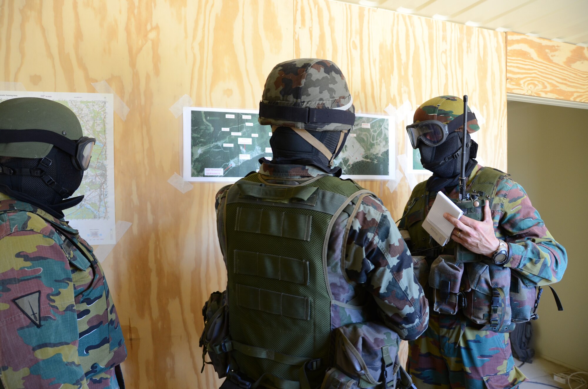 Belgian Joint Terminal Attack Control instructors talk to a Slovenian JTAC at the Combat Outpost Defense lane at Grafenwoehr Training Area, Germany, June 28, 2011. The COP Defense lane trains JTACs on tactics, techniques and procedures for defending a COP against insurgent attack. They are wearing facemasks and eye protection due to the use of Close Combat Mission Capability Kit rounds, which enhance the realism of training. Allied Strike is Europe's premier Close Air Support exercise, held annually to conduct robust, realistic CAS training that helps build partnership capacity among Allied NATO nations and refine the latest operational CAS tactics. (Photo by Molly Hayden, U.S. Army Garrison Grafenwoehr Public Affairs) 