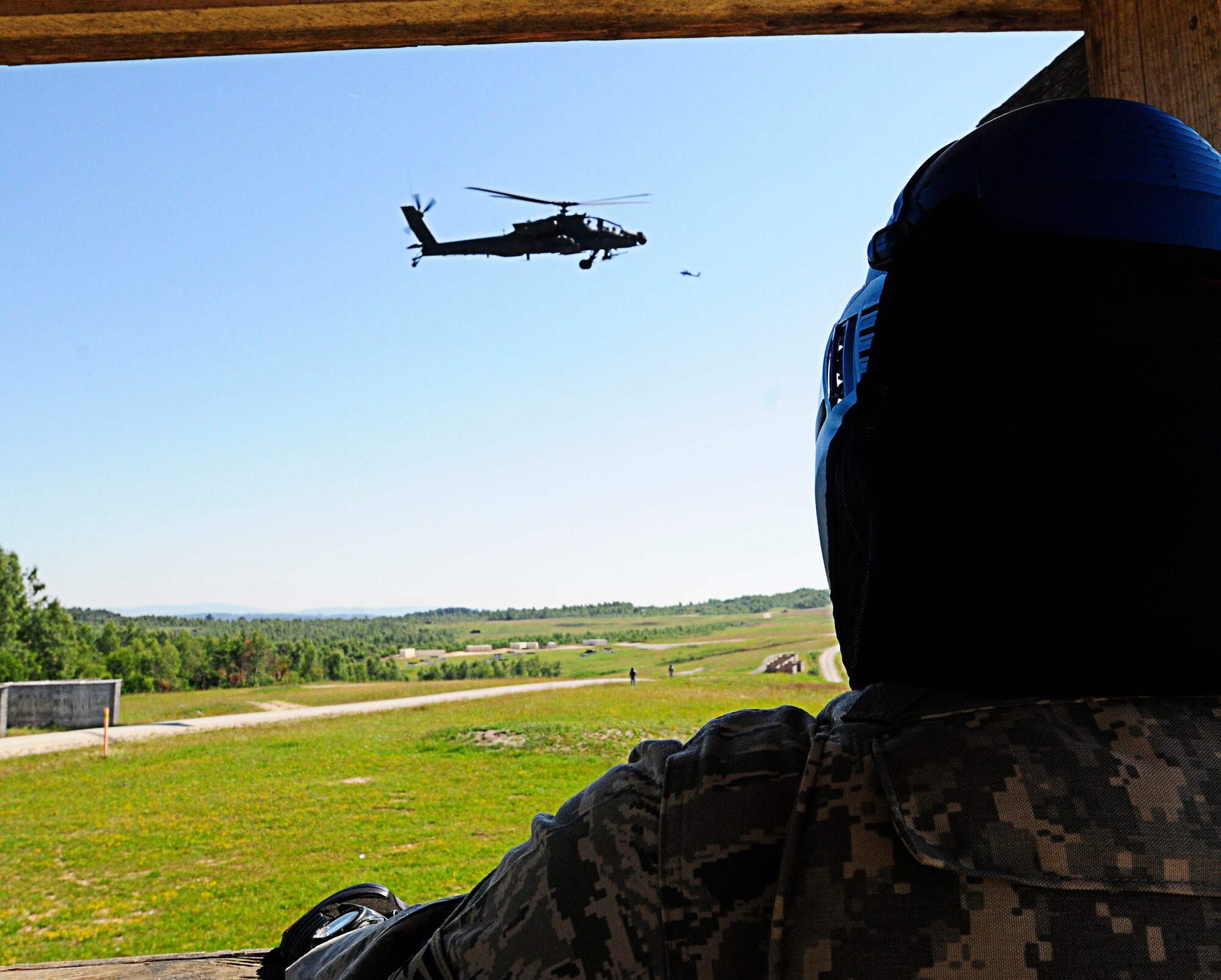 Senior Airman Derrick Love, 435th Security Forces Squadron, watches an AH-64 Apache attack helicopter provide simulated Close Air Support at the Combat Outpost Defense lane at Grafenwoehr Training Area, Germany, June 28, 2011. The COP Defense lane trains Joint Terminal Attack Controllers on tactics, techniques and procedures for defending a COP against insurgent attack. Allied Strike is Europe’s premier CAS exercise, held annually to conduct robust, realistic CAS training that helps build partnership capacity among Allied NATO nations and refine the latest operational CAS tactics. (U.S. Air Force photo by Airman 1st Class Desiree W. Esposito)