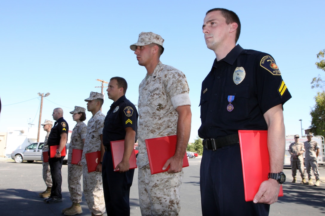 Civilian police officers and Marines from Camp Pendleton stand in formation after receiving an award for rescuing a missing veteran on the base hunting grounds, June 30.