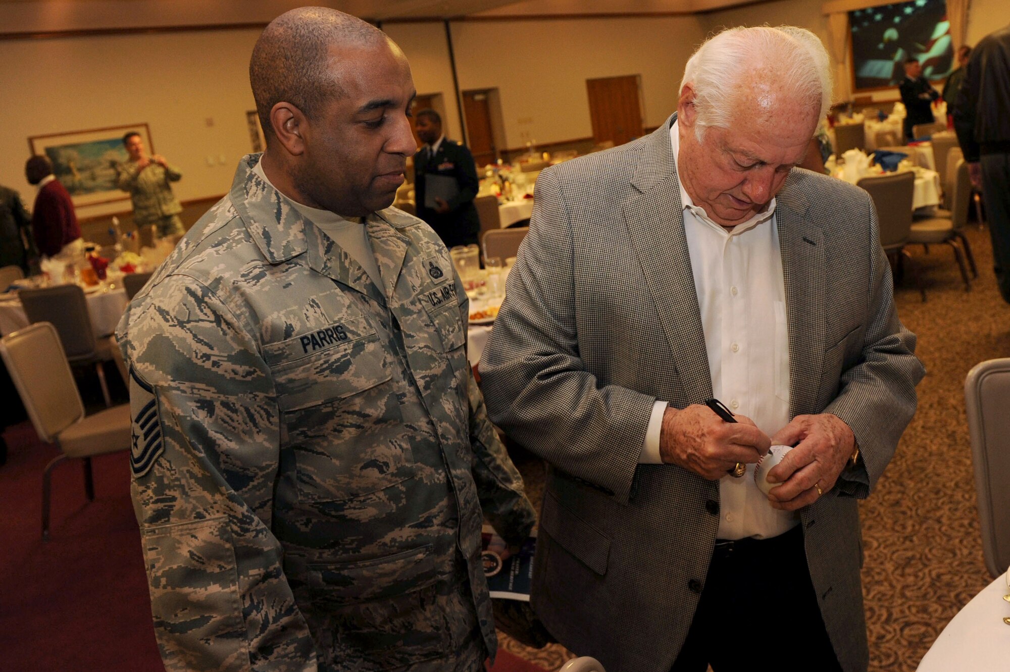 NELLIS AIR FORCE BASE, Nev. -- Tommy Lasorda, former Los Angeles Dodgers manager and National Baseball Hall of Fame inductee, autographs a baseball for Master Sgt. Gary Parris. Mr. Lasorda was the guest speaker during the National Prayer Breakfast at the Nellis Club Feb. 23. (U.S. Air Force photo by Airman 1st Class Daniel Hughes)




