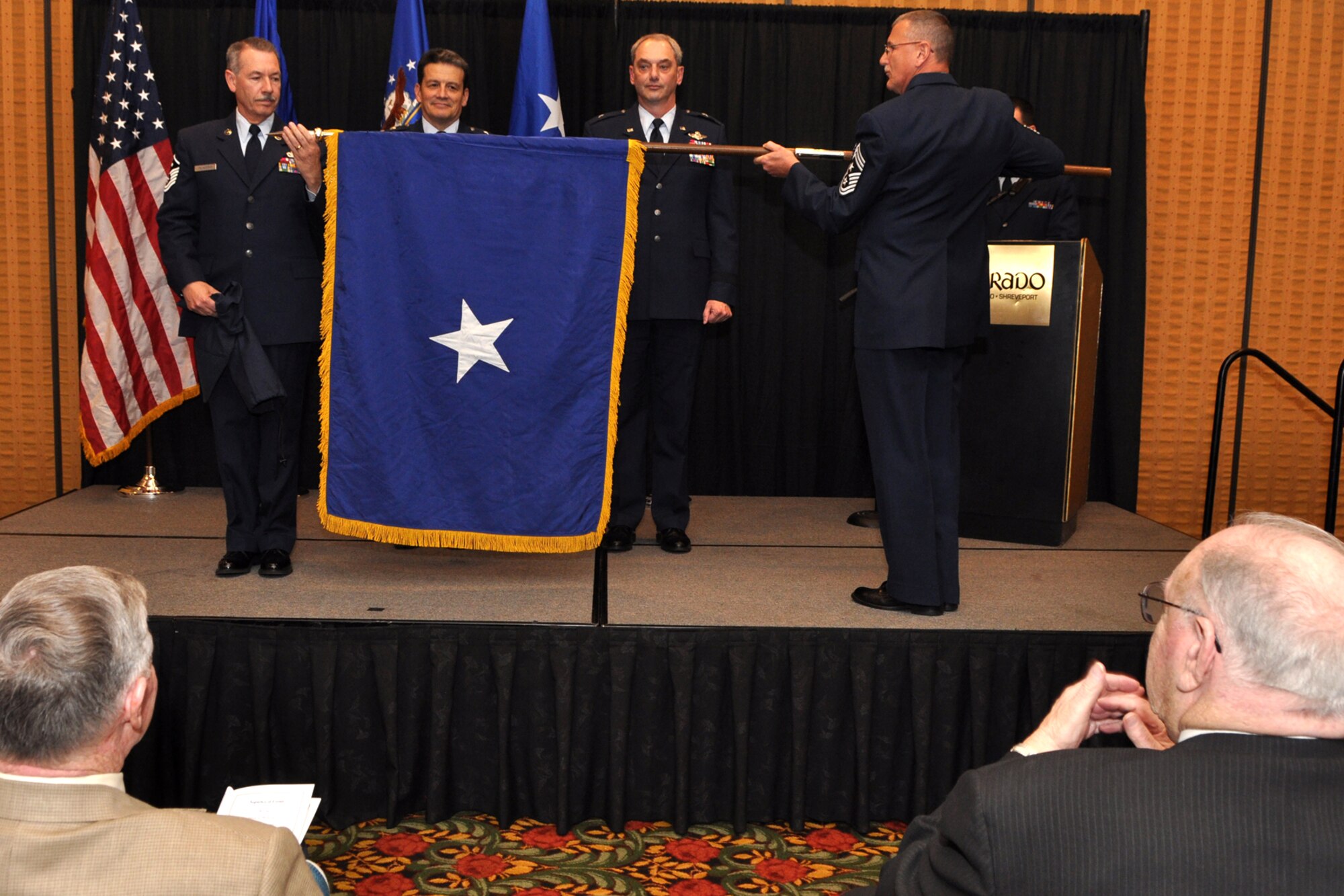 Maj. Gen. Frank Padilla, commander, 10th Air Force, (second from left) and Brig. Gen. John J. Mooney III, (third from left) commander of the 307th Bomb Wing, Barksdale Air Force, La., watch as a general officer's flag is unfurled by Master Sgt. James Taliaferro and Chief Master Sgt. Keith St. Aubin, during General Mooney's pinning-on ceremony at the Eldorado Hotel in Shreveport, La., Feb. 25, 2010. General Padilla was the presiding official for the ceremony. Chief St. Aubin is the command chief for the 307th BW and Sergeant Taliaferro is the first sergeant for the 307th Security Forces Squadron. Approximately 70 family members and friends were in attendance, some traveling in from as far away as Maine for the event. (Photo by Jeff Walston)