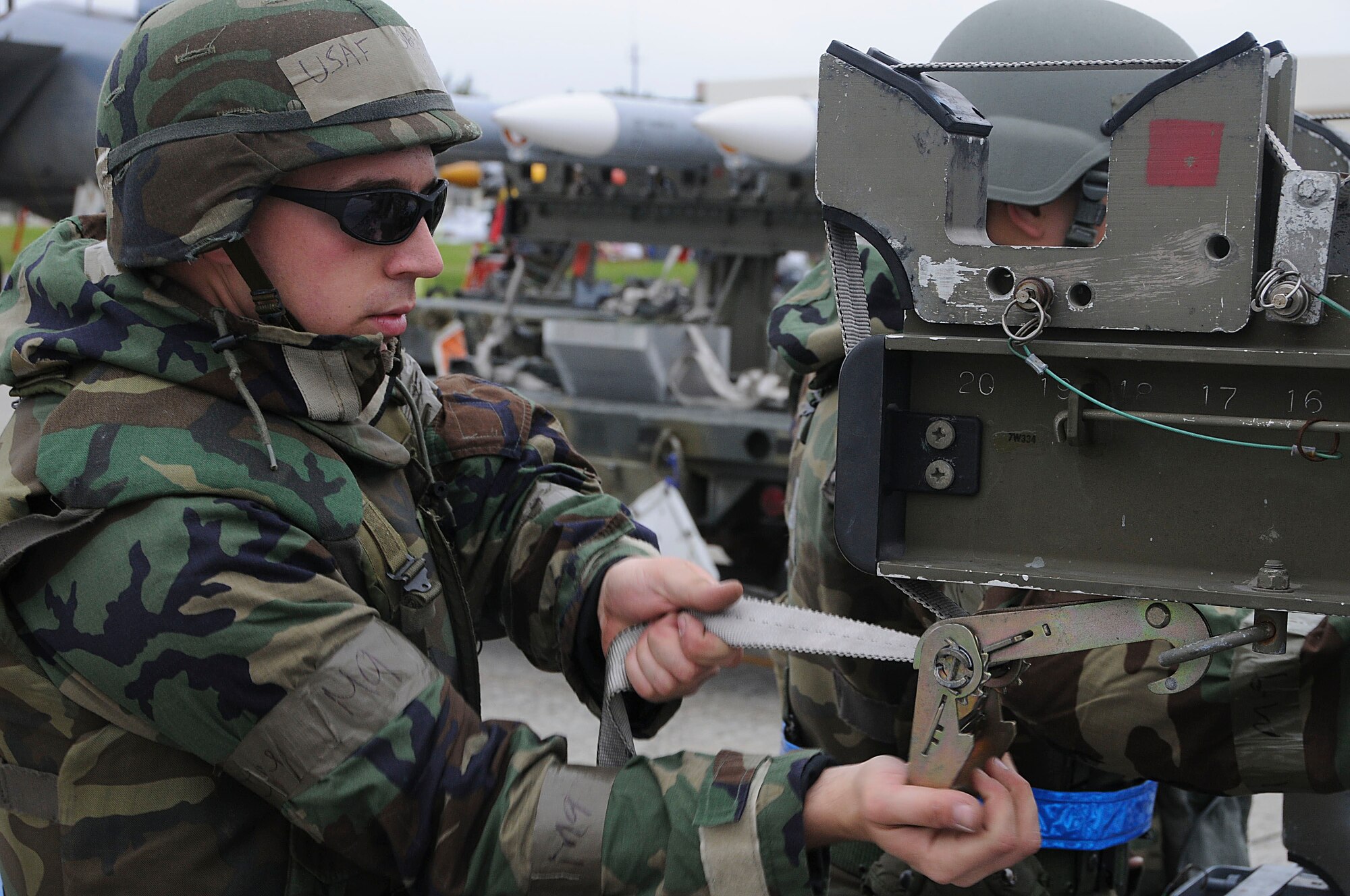Senior Airman Matthew Curiale, 44th Aircraft Maintenance Unit weapons load crew member, fastens the strap of the munitions trailer during Beverly High 11-03, a local operational readiness exercise at Kadena Air Base, Japan, March 1. Fastening the straps ensures that the missiles are secure and do not risk falling off when they are moved. (U.S. Air Force photo/ Staff Sgt. Darnell T. Cannady)