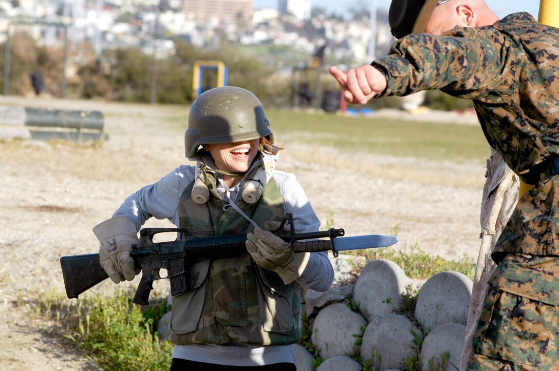 Rachel Couch, a reporter for KYMA-11, NBC Television News in Yuma, Ariz., is directed toward the Bayonet Assault Course dummies by a drill instructor, after her helmet covered her eyes during the exercise.