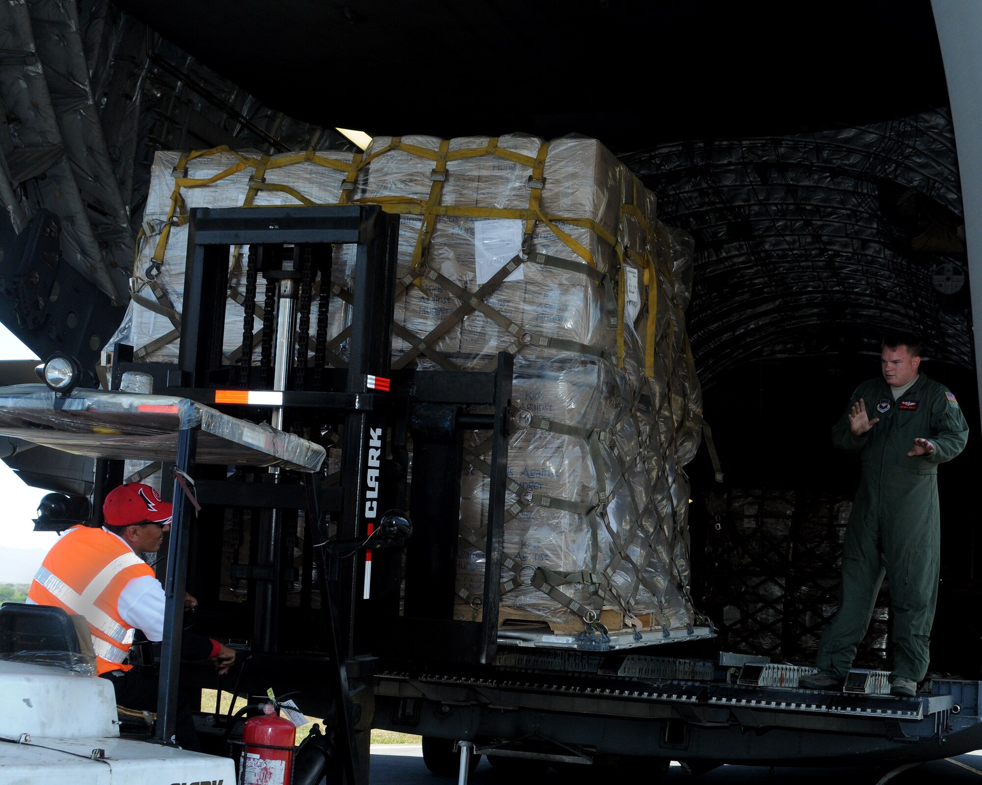 JOINT BASE CHARLESTON, S.C. -- Staff Sgt. Mathew Johnson loadmaster, 58th Airlift Squadron, Altus Air Force Base, Okla., guides a forklift operator at Managua Airport, Nicaragua, as he unloads pallets off of a C-17 Globemaster III from Altus AFB Feb. 20. The delivery was possible because of the Denton Program, which allows donors to use space available on U.S. military cargo aircraft to transport humanitarian goods and equipment to people in need. (U.S. Air Force photo by Airman 1st Class Kenneth W. Norman/ Released 97th Air Mobility Wing Public Affairs)