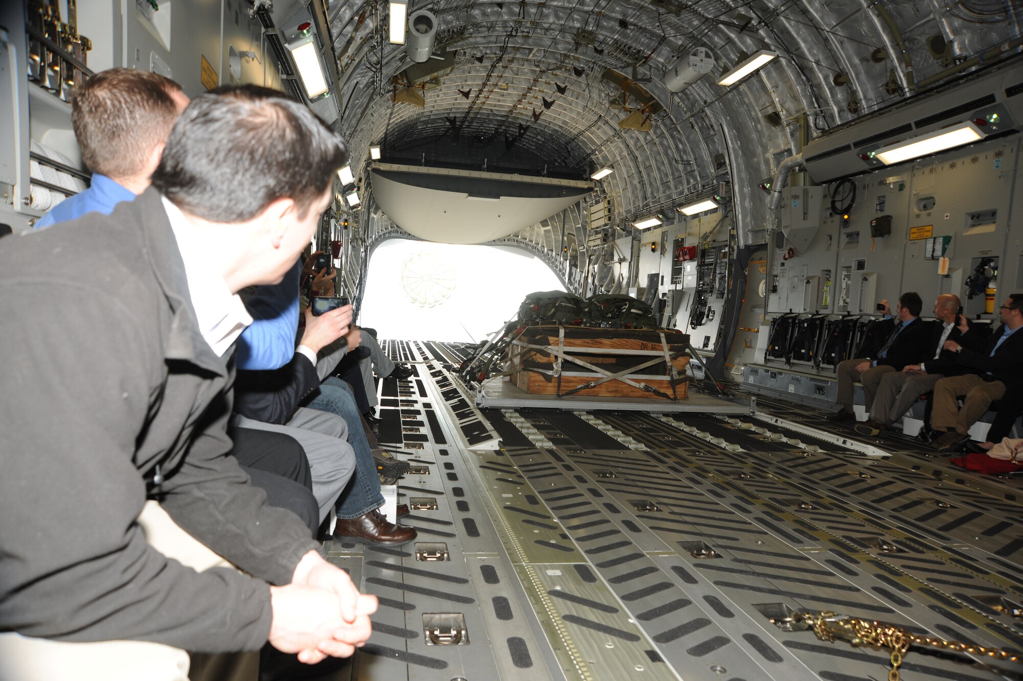 Congressional staff members, aboard a 14th Airlift Squadron C-17 Globemaster III, watch as a pallet begins to airdrop over North Field, Joint Base Charleston, S.C., on Feb. 18 2011. The Congressional staffers spent the entire day learning about airlift, airdrop and aeromedical evacuation as part of an orientation designed to give them a better understand of Air Mobility Command’s mission. (U.S. Air Force Photo/Master Sgt. Jeff Capenos)