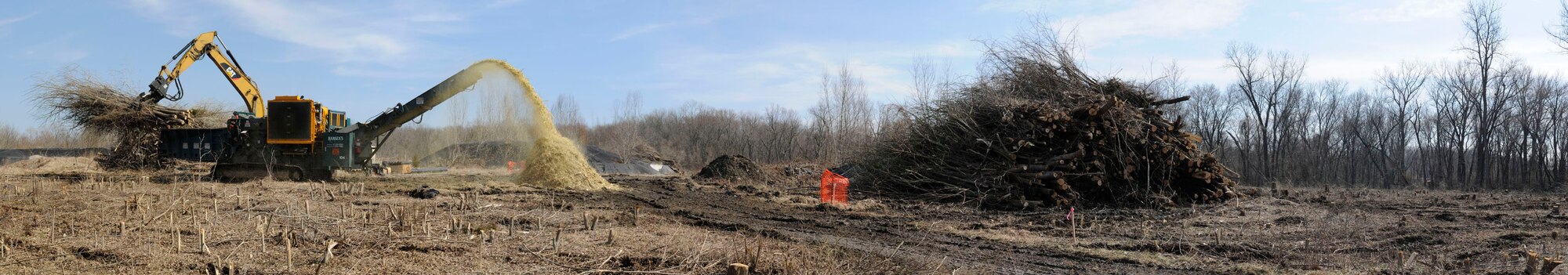 An excavator drops trees into an industrial chipper after they were removed from a landfill site Mar. 1, 2011 at Scott Air Force Base, Ill. The base landfill that operated from the 1940's until 1976 is being capped as part of a $20 million project. The 36 acre landfill engineered capping will consist of a one-foot thick gravel layer for methane gas collection, a geosynthetic liner to cover all of the landfill waste and prevent future contact with the waste, a drainage layer to funnel rainwater off of the liner, and two feet of clean soil to serve as a protective layer for the liner and to support vegetative growth. As part of the landfill capping project, the first phase is to remove the trees that have grown on top of the landfill. Capping the former base landfill is part of the Environmental Restoration Program efforts to meet the Air Force's goal of having remedies in place at contaminated sites by the end of 2012. (U.S. Air Force Photo/Staff Sgt. Brian J. Valencia)