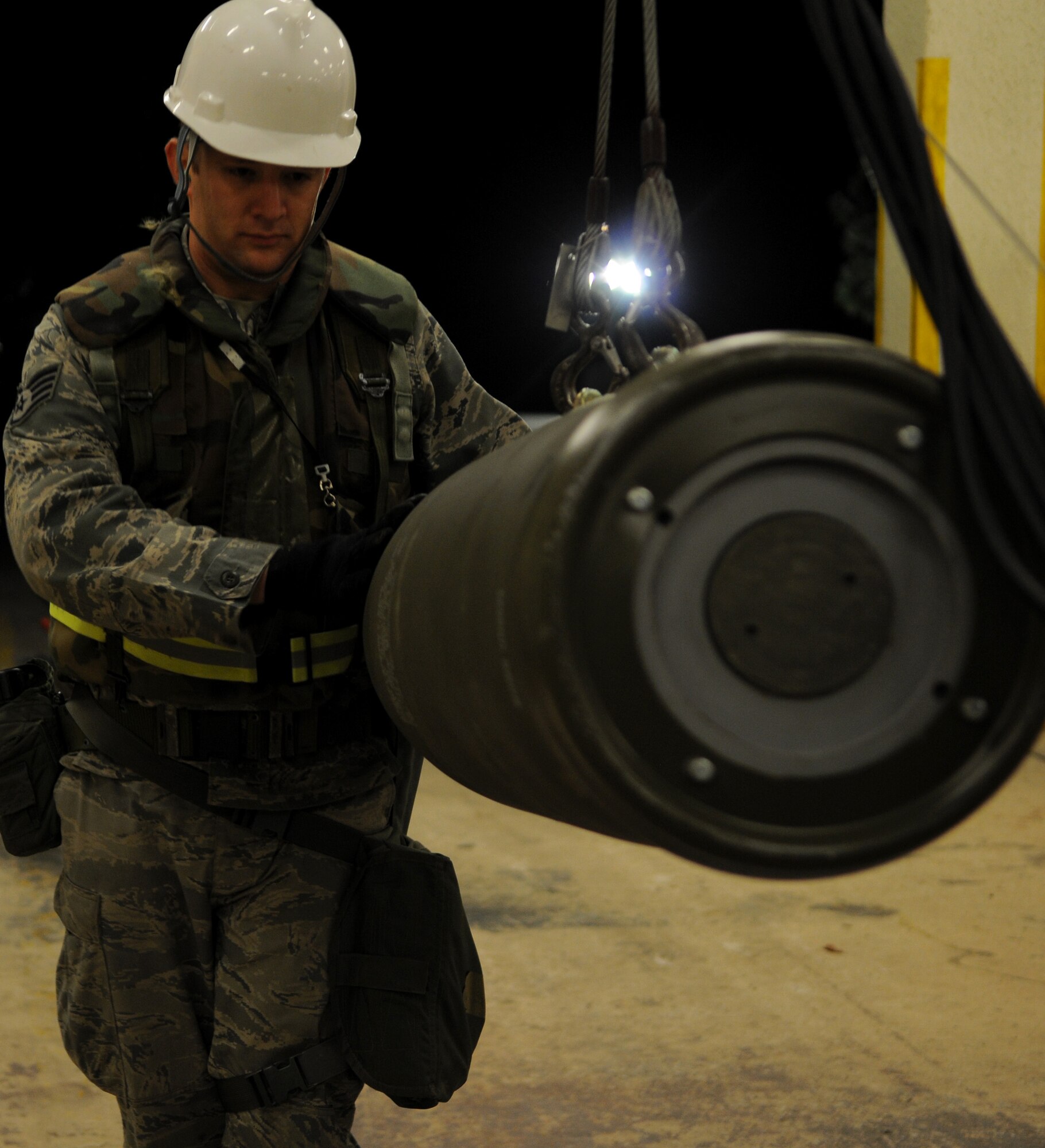 Staff Sgt. Matthew Owen, 18th Munitions Squadron munition systems craftsman, guides Mark 83 bomb bodies into a harness during Beverly High 11-03, a local operational readiness exercise, at Kadena Air Base, Japan, March 3. The LORE is designed to test the ability of Kadena Airmen to operate during a variety of attack scenarios. (U.S. Air Force photo/Airman 1st Class Jarvie Z. Wallace)