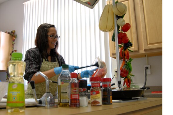 Finding her inner Julia Child, Alice Torres, Health and Wellness Center dietitian, adds red peppers to a dish during a cooking demonstration class at the HAWC, Feb. 24. The HAWC conducts monthly cooking classes as a way to promote healthy lifestyles among the base community. (Air Force photo by Kate Blais)