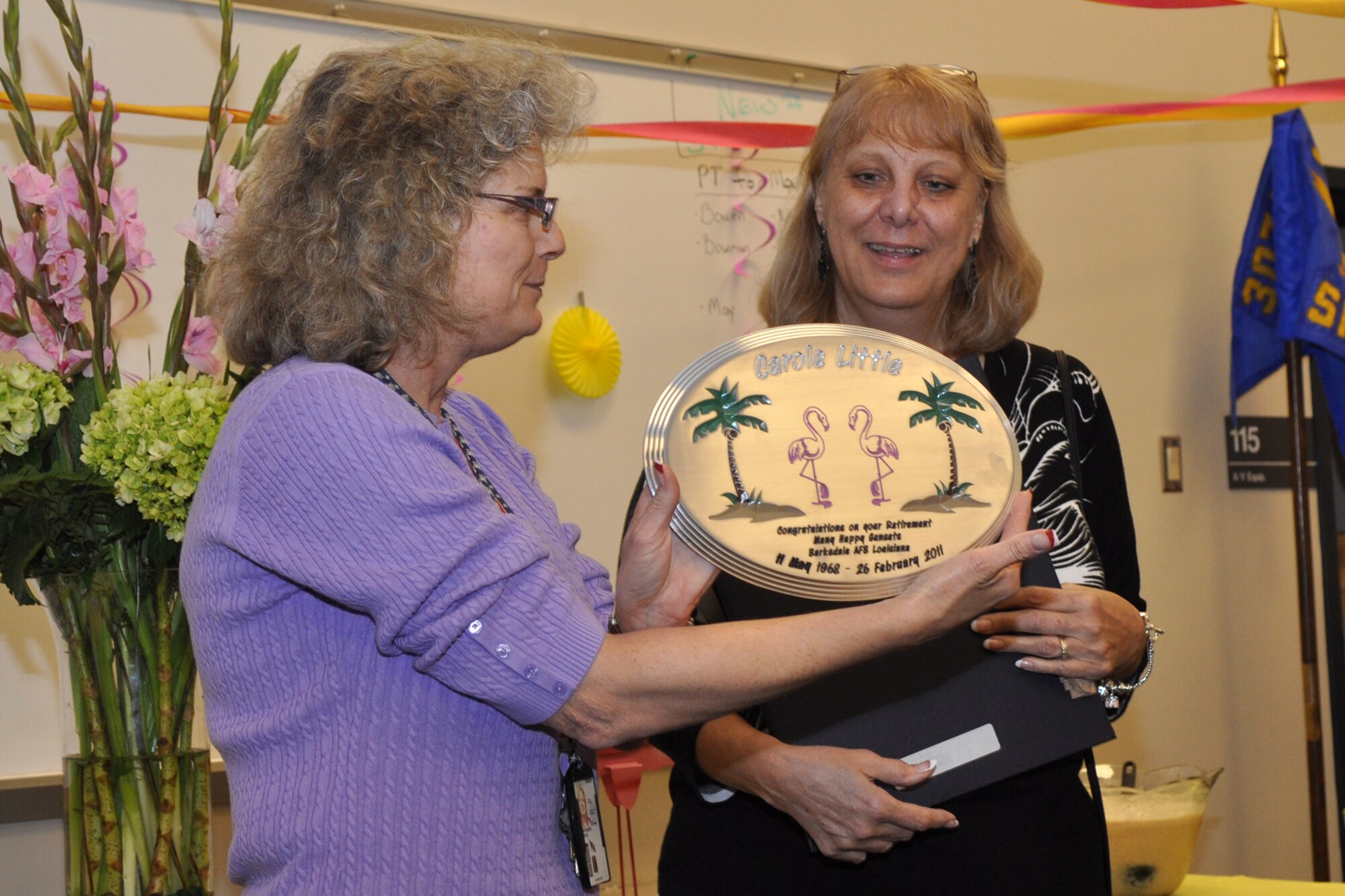 Taryn Montgomery, (left) budget officer, 307th Bomb Wing, presents a plaque to Carole Little, a budget analyst for the 307th BW, during a cake and punch social celebrating Ms. Little's retirement at Barksdale Air Force Base, La., Feb. 24, 2011. Ms. Little, who started her career in the Regular Air Force, is retiring after 34 years of faithful service to her country. She is originally from Pennsylvania, and will be relocating to Florida with her husband John to enjoy her retirement years. (U.S. Air Force photo/ Tech. Sgt. Jeff Walston) 