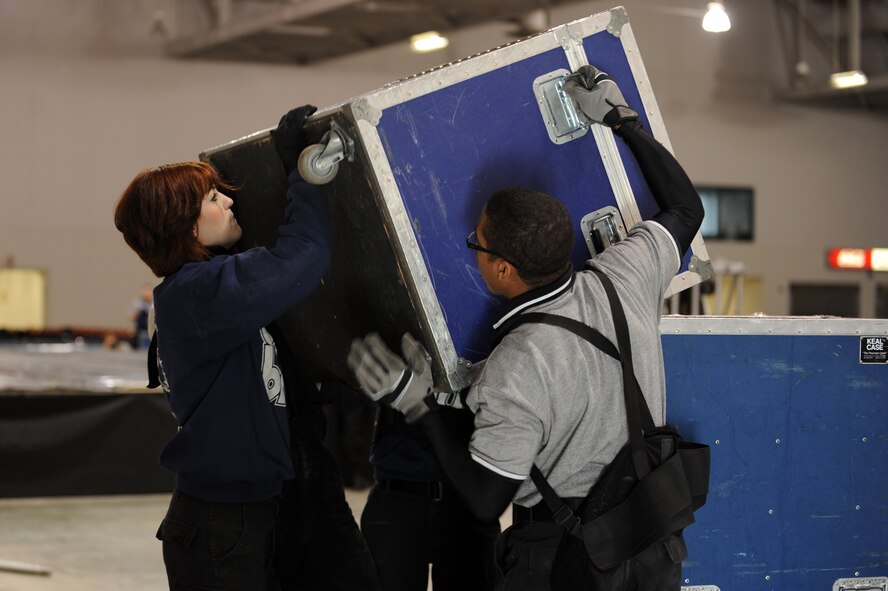 MINOT, N.D. –  Airman 1st Class Jette Warnick, Tops in Blue vocalist, and Airman 1st Class Edward Whittle Jr., Tops in Blue keyboard player, unload the equipment truck in preparation for the Tops in Blue performance at the State Fair Grounds here Feb. 23. Tops in Blue serves as an expeditionary entertainment unit to provide quality entertainment from within Air Force resources for the Air Force family and personnel. (U.S. Air Force photo/Airman 1st Class Jose Hernandez)