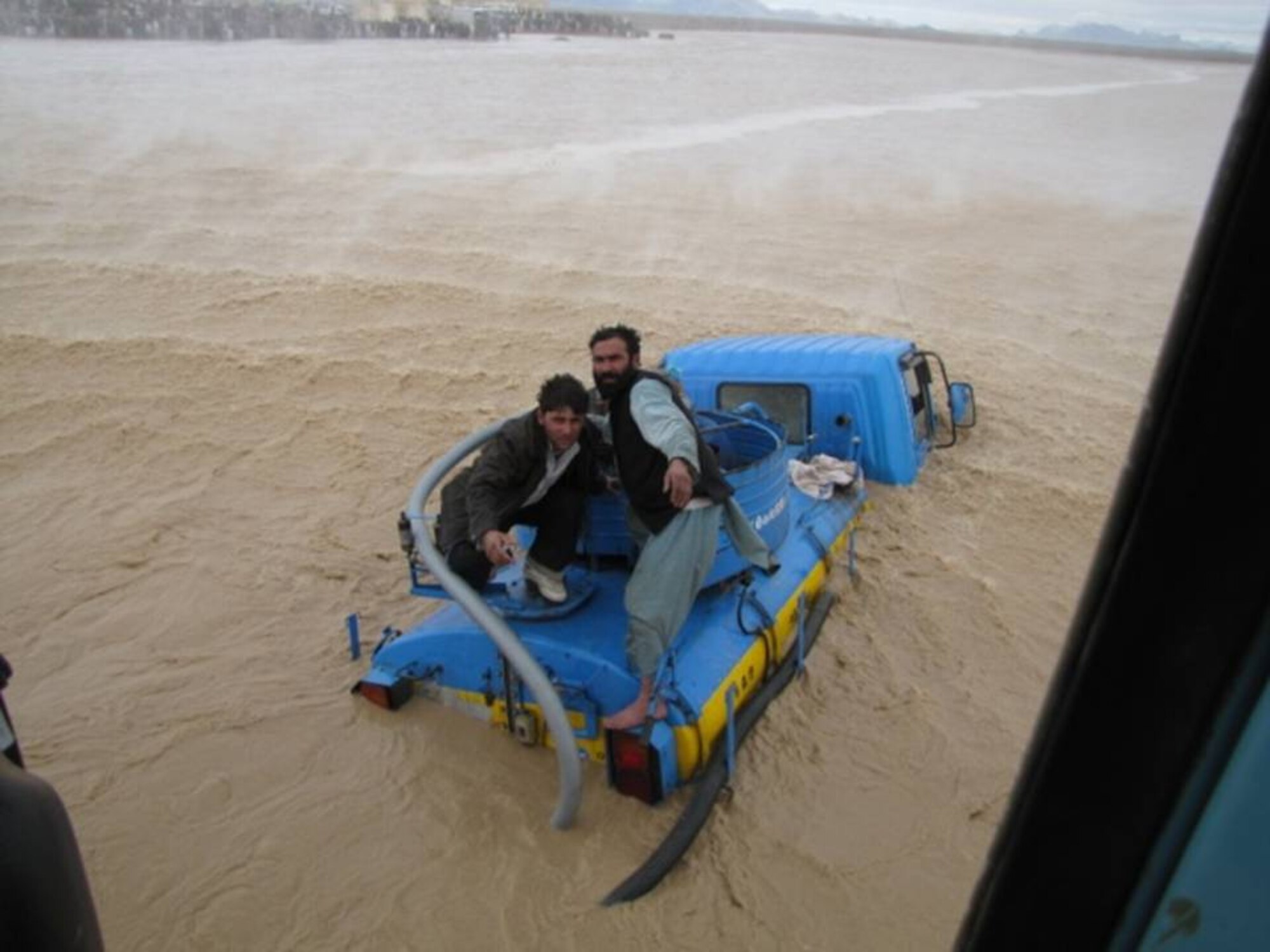 KANDAHAR, Afghanistan - An Afghan Air Force Mi-17 transport helicopter hovers near two men stranded by flash floods. The men were quickly pulled into the helicopter and rescued on Mar. 1. (U.S. Air Force photos). 