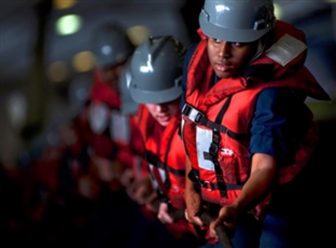 U.S. Navy sailors man a line in a hangar bay during a replenishment on board the aircraft carrier USS Carl Vinson which is underway in the Arabian Sea, Feb. 25, 2011. A replenishment is a method of transferring fuel, munitions and stores from one ship to another while at sea.