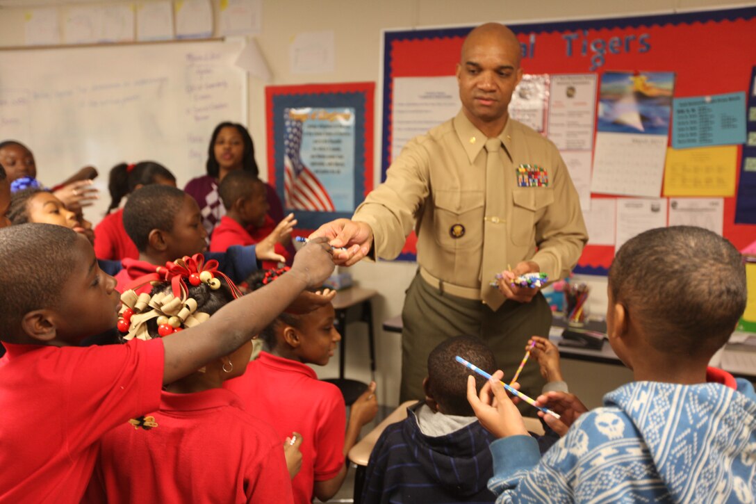 Maj. Jason Davis, the 4th Marine Aircraft Wing avionics officer, passes out pencils to students at Sarah T. Reed Elementary School March 2.