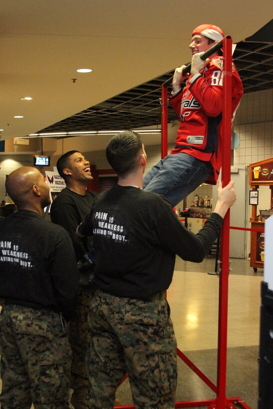 WASHINGTON, D.C.- A Washington Capitals fan does pull-ups as recruiters from Recruiting Station Baltimore, Md. look on. Enhanced area canvassing events like the Capitals game yield solid leads for the recruiters as they search the Washington area for highly qualified men and women who are interested in becoming Marines. (US Marine Corps photo by Lance Cpl. David Flynn)