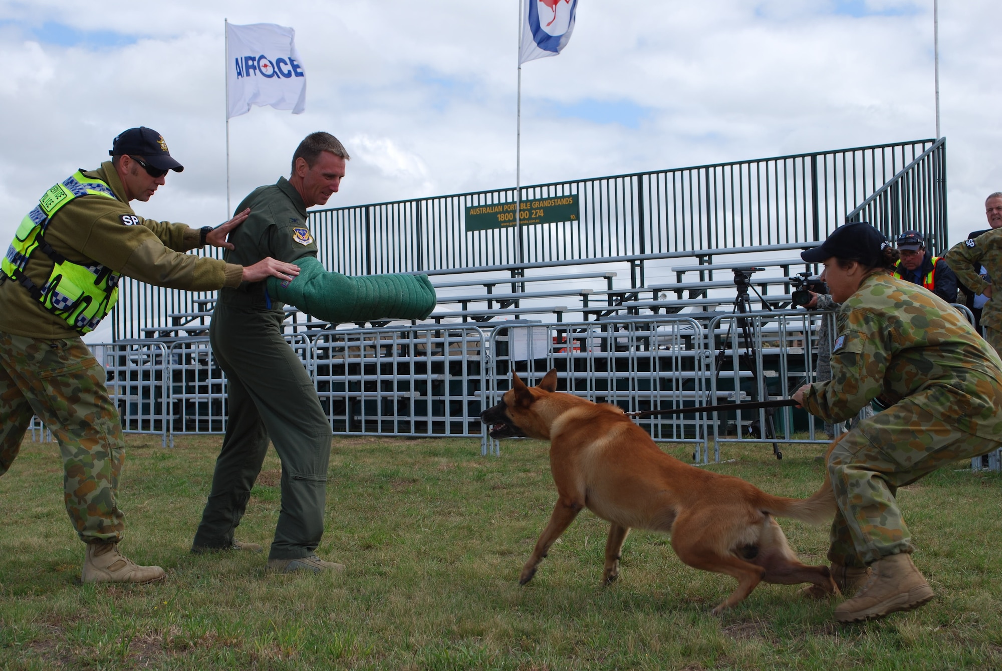 Col. Seth Bretscher assists the Royal Australian Air Force's security team by taking a bite from Rex, a Belgian Malinois member of the K-9 team, as handler RAAF  Leading Aircraft Woman Cheryl Chaffey holds him back during the Avalon 2011 Australian International Airshow in Geelong, Australia, March 3, 2011. Colonel Bretscher is the Vice Commander of the 613th Air and Space Operations Center at Joint Base Pearl Harbor-Hickam, Hawaii, and is serving as the Air Force mission commander during the event. A variety of Air Force aircraft are displayed at the air show and some aerial performances are also included. Through participating in air shows and other regional events, the United States demonstrates its commitment to the security of the Asia-Pacific region, promotes the standardization and interoperability of equipment, and displays capabilities critical to the success of current and future military operations. (U.S. Air Force photo/Staff Sgt. LuCelia Ball)