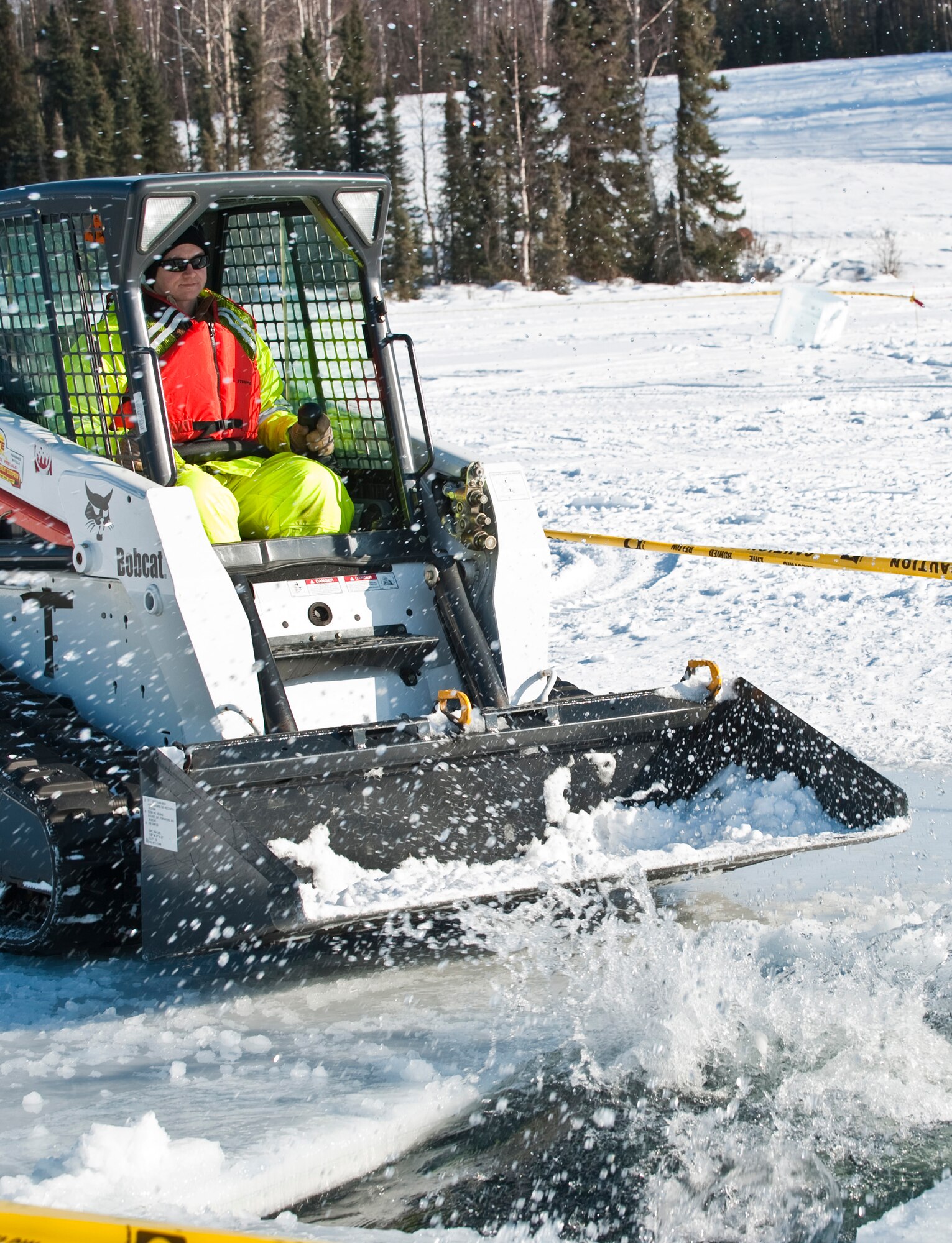 JOINT BASE ELMENDORF-RICHARDSON, Alaska -- Tech. Sgt. Lucas Clark, 611th Civil Engineer Squadron, uses a Bobcat to push a block of ice back into the water March 1 at JBER's Six-Mile Lake during the annual Ice Operations Exercise. Approximately a combined 60 members from the 611th CES, U.S. Coast Guard, the Navy's Supervisor of Salvage, Alaska Department of Environmental Conservation and the Alaska Chadux Corporation participated in the annual exercise, where participants practice various oil spill clean-up drills in preparation if there was ever an event here in Alaska. (U.S. Air Force photo by Senior Airman Christopher Gross)