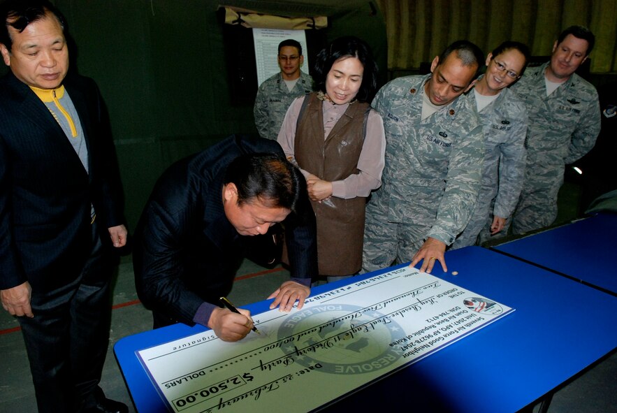 Members of U.S. Forces Korea’s Good Neighbor Program sign a check before presenting it to members of the Rush Park staff Feb. 25, 2011, at Osan Air Base, Republic of Korea. The Rush Park support staff will use the donated money to host a victory party for Key Resolve participants following the end of the 10-day exercise. (U.S. Air Force photo by Staff Sgt. Rachel Martinez)