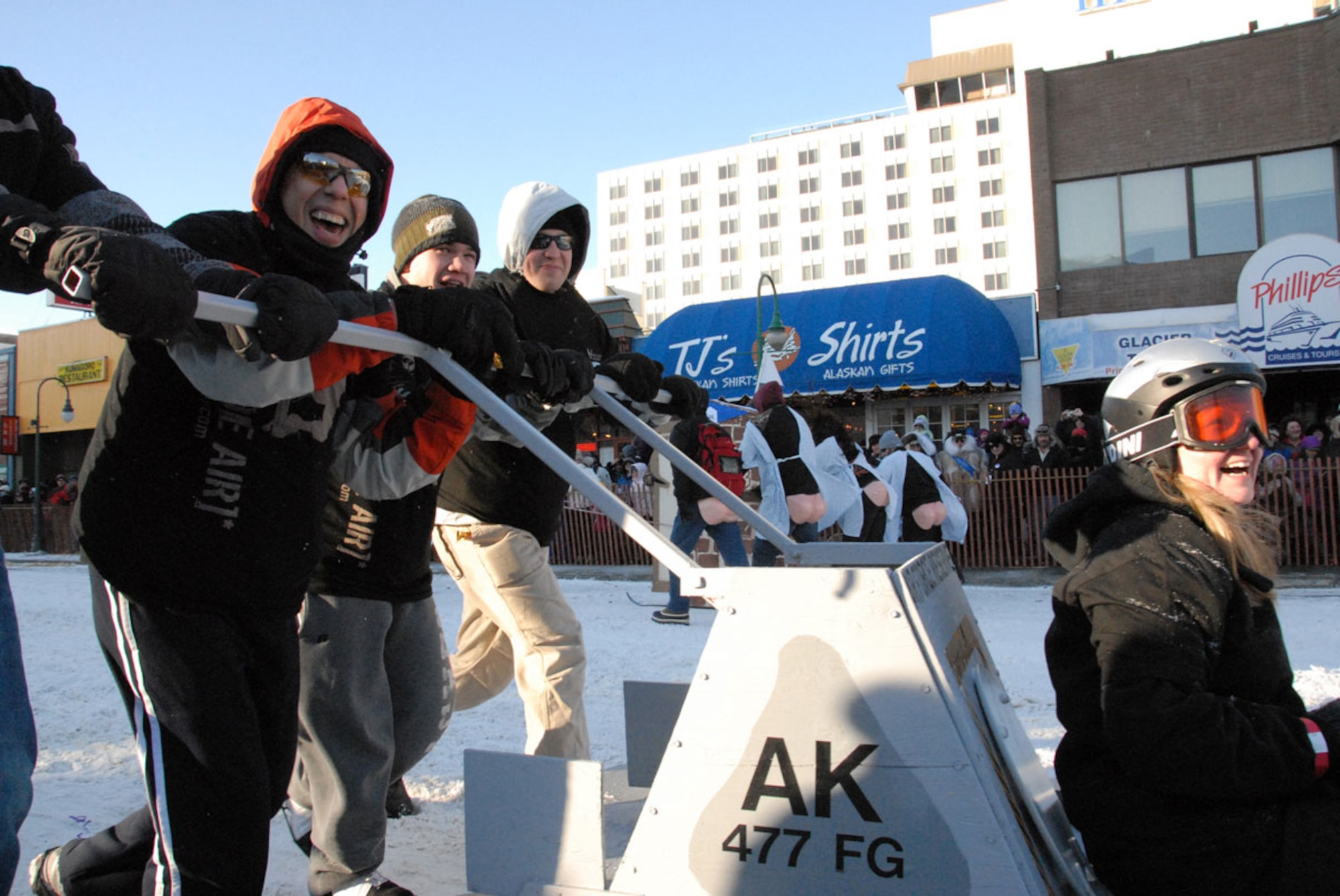 The “Part-time Pushers,” the Air Force Reserve team from the 477th Fighter Group, react to the Fur Rondy crowds assembled to watch the world’s largest outhouse races in downtown Anchorage, Feb 27. Pushers pictured are, from left, Tech. Sgt. Jose Garza, Airman 1st Class Ryan Weeks and Tech. Sgt. Travis Schlapbach.  Tech. Sgt. Leelah Dill “piloted” the outhouse. (Air Force photo/Maj. Lisa Reaver)