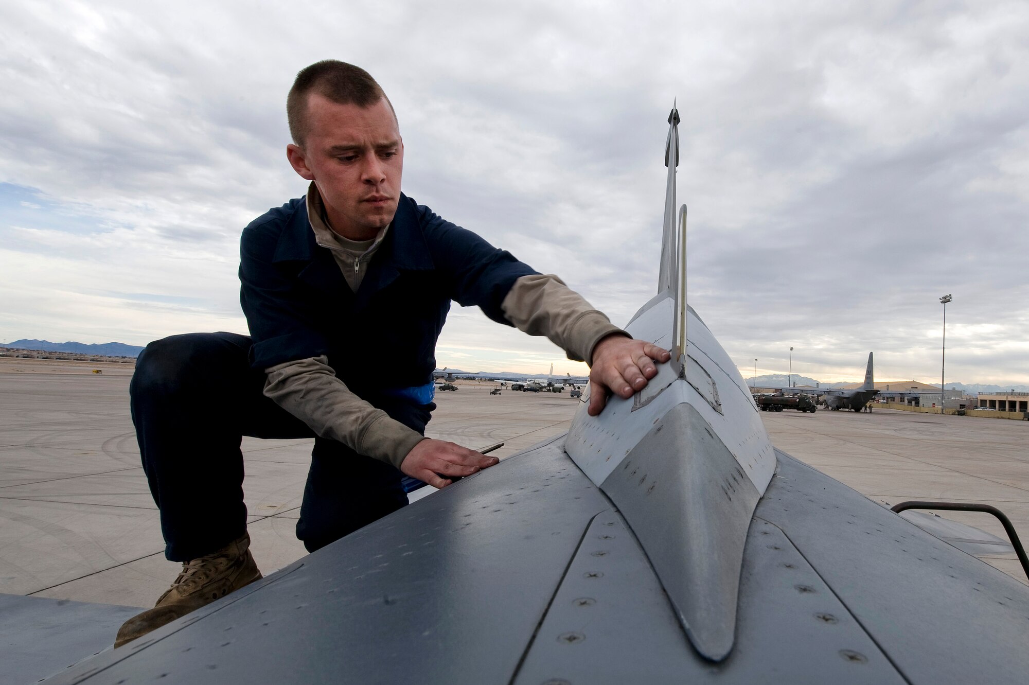 NELLIS AIR FORCE BASE, Nev. --  Senior Airman Dominic Dizes, 20th Aircraft Maintenance Squadron crew chief, Shaw Air Force Base, S.C., inspects the top of a F-16 Fighting Falcon for missing screws during Red Flag 11-3, March 1.  Red Flag is a realistic combat training exercise involving the air forces of the United States and its allies. The exercise is hosted north of Las Vegas on the Nevada Test and Training Range. (U.S. Air Force photo by Senior Airman Brett Clashman)
