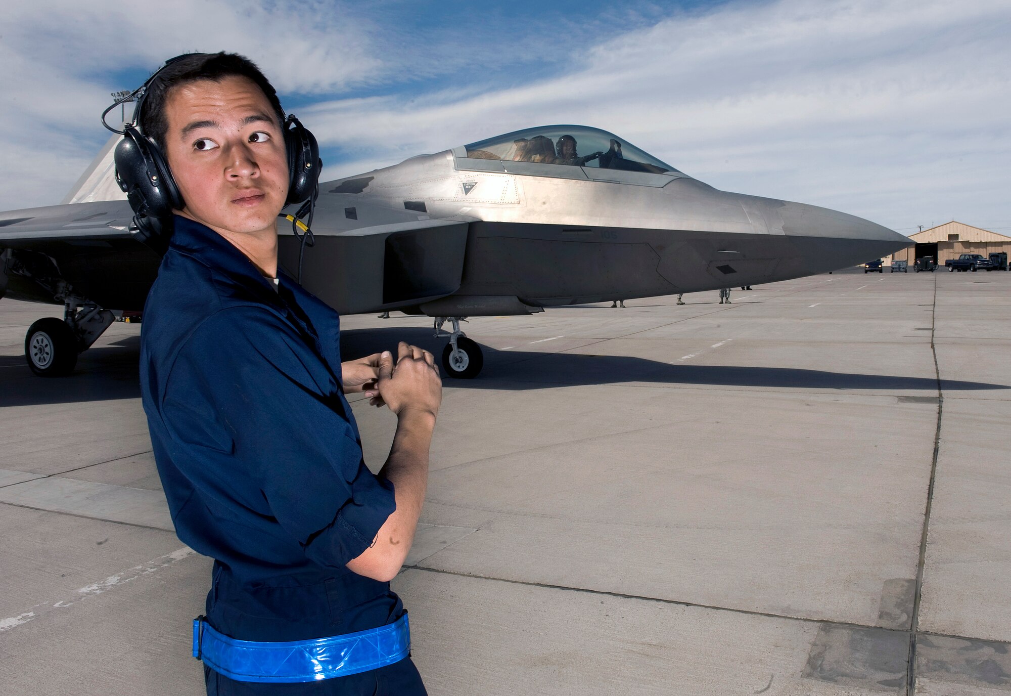 NELLIS AIR FORCE BASE, Nev. --  Airman 1st Class Ryan Pottmeyer, 3rd Aircraft Maintenance Squadron crew chief, Elmendorf Air Force Base, Alaska, looks to see if the row is clear to marshal out an F-22 Raptor during Red Flag 11-3, March 1.  Red Flag is a realistic combat training exercise involving the air forces of the United States and its allies. The exercise is hosted north of Las Vegas on the Nevada Test and Training Range.(U.S. Air Force photo by Senior Airman Brett Clashman)
