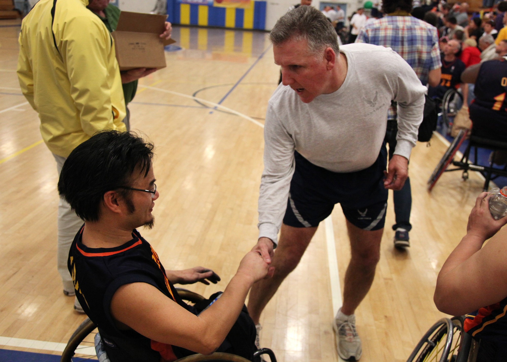 TRAVIS AIR FORCE BASE, Calif. -- Col. Jay Flournoy, 349th Air Mobility Wing commander, presents a challenge coin to Mr. Don Bearden at halftime of a wheelchair basketball game between Team Travis leadership and the Golden State Road Warriors at the Travis Fitness Center, Feb. 26, 2011. The Road Warriors are one of the top wheelchair basketball teams in the country, and play as members of the National wheelchair Basketball Association.  
The Airmen received an hour of training in the wheelchairs and were spotted 20 points, but the Road Warriors quickly asserted their dominance on the court.  The friendly, but spirited game hosted by the USO was cheered on by more than 300 members of the Team Travis community.  (U.S. Air Force photo / Lt.Col. Robert Couse-Baker)
