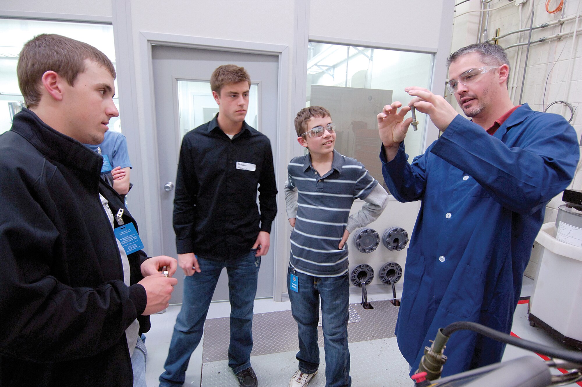 Ron Koepp, a Tinker materiels engineer, shows students a metal bolt stretched to its limit as an example of tensile and failure tests he performs in the Structural Integrity Lab of the Oklahoma City Air Logistics Center. Students toured labs Feb. 24 during the annual Oklahoma Society of Professional Engineers Engineer for a Day program. Students from left are; Marshall Hartley, Harrah High School junior; Braden Hobaugh, Harrah senior; and A.J. Race, Mustang High School ninth-grader. (Air Force photo by Margo Wright)