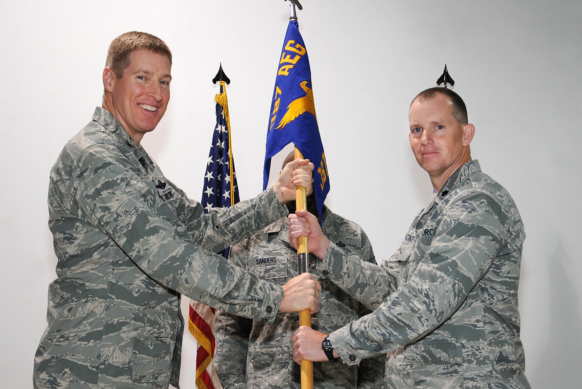 Col. Tal Metzgar, 387th Air Expeditionary Group commander, passes the 387th Expeditionary Logistics Readiness Squadron guidon to Lt. Col. Christopher Boone, the new commander of the squadron, during a change of command ceremony at an undisclosed location in Southwest Asia March 2. Colonel Boone assumed command of the Combat Truckers from Lt. Col. Raymond Cirasa who will soon be redeploying. (U.S. Air Force photo by Senior Airman Cynthia Spalding)