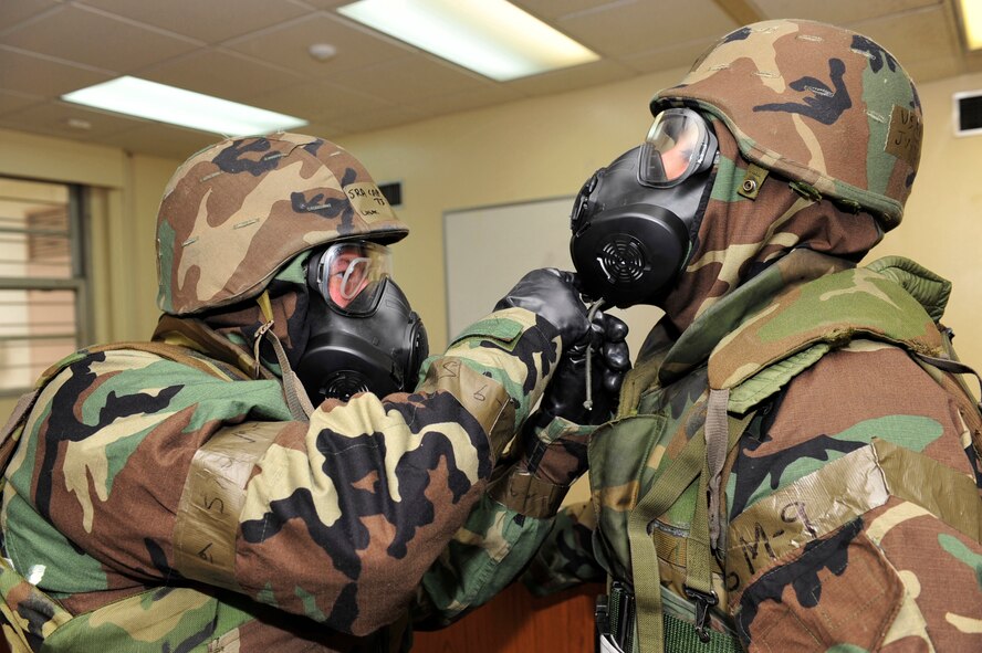 Senior Airman Timothy Carlisle, 909th Aircraft Maintenance Squadron electrical and environmental systems technician, secures Airman 1st Class Justin Glavaris', 909th Aircraft Maintenance Squadron guidance control systems technician, chin strap during the local operational readiness exercise on Kadena Air Base, Japan, March 3. During scenarios where a chemical agent may be present, it’s important for Airmen to perform “buddy checks” to ensure each person’s gear is properly donned.  (U.S. Air Force photo/ Staff Sgt. Lakisha A. Croley)