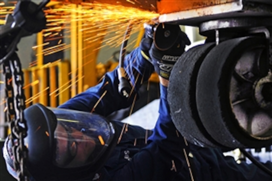 U.S. Navy Petty Officer 2nd Class Jason Jacobs uses a high-speed cutting tool to remove part of an aircraft tow-bar trailer aboard the amphibious assault ship USS Kearsarge, which is under way in the Gulf of Aden, Feb. 26, 2011. The Kearsarge is the command ship of the Kearsarge Amphibious Ready Group, supporting maritime security operations and theater security cooperation efforts in the U.S. 5th Fleet area of responsibility.