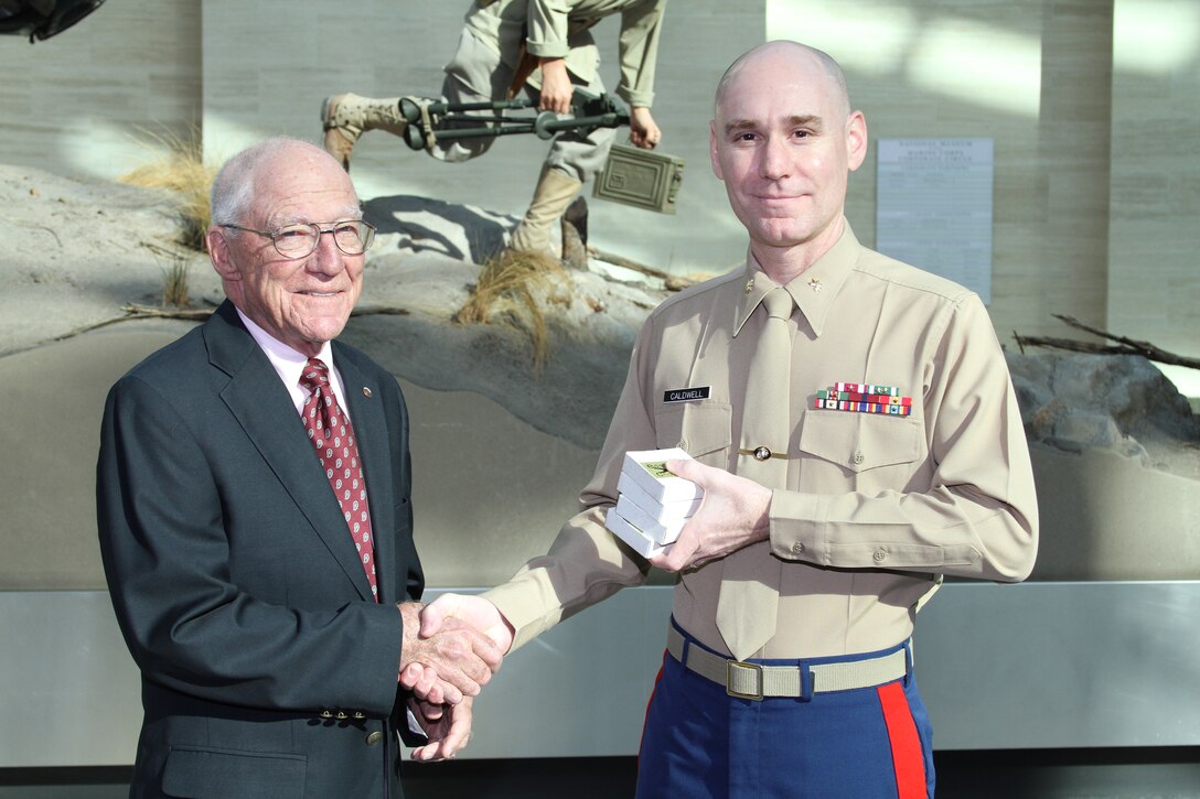 Major John O. Caldwell, director of public affairs, Marine Corps Recruiting Command, accepts four original 16mm film reels containing Marine Corps commercials from Mr. Richard Tschudin, a retired Hollywood director and former sailor. Tschudin served in the Navy during the Korea War era and later directed several commercials for the Marine Corps. Tschudin, who traveled from Fallbrook, Calif., told his son that donating these films meant more to him than receiving an Oscar or an Emmy because of his family’s tie to the military. The film reels will be archived and preserved by the National Museum of the Marine Corps.