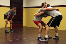 All-Marine wrestler 1st Lt. John Cox, 26, from Grand Haven, Mich., watches Minnesota Storm Wrestling Coach Dan Chandler demonstrate a body lock takedown on teammate Sgt. Donavan Depatto, a 26-year old from Monticello, Minn. Cox wrestles in the 66 kilogram weight class and Depatto wrestles at 60 kilograms. Chandler, a well-known international coach with multiple wrestling accolades at the World and Olympic levels, said the Marine Corps has a fabulous wrestling program and looks forward to seeing how they do at the U.S Open.