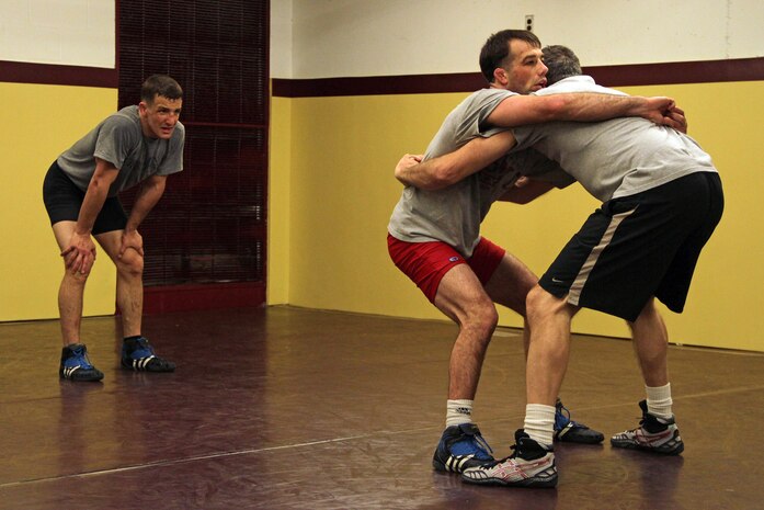All-Marine wrestler 1st Lt. John Cox, 26, from Grand Haven, Mich., watches Minnesota Storm Wrestling Coach Dan Chandler demonstrate a body lock takedown on teammate Sgt. Donavan Depatto, a 26-year old from Monticello, Minn. Cox wrestles in the 66 kilogram weight class and Depatto wrestles at 60 kilograms. Chandler, a well-known international coach with multiple wrestling accolades at the World and Olympic levels, said the Marine Corps has a fabulous wrestling program and looks forward to seeing how they do at the U.S Open.