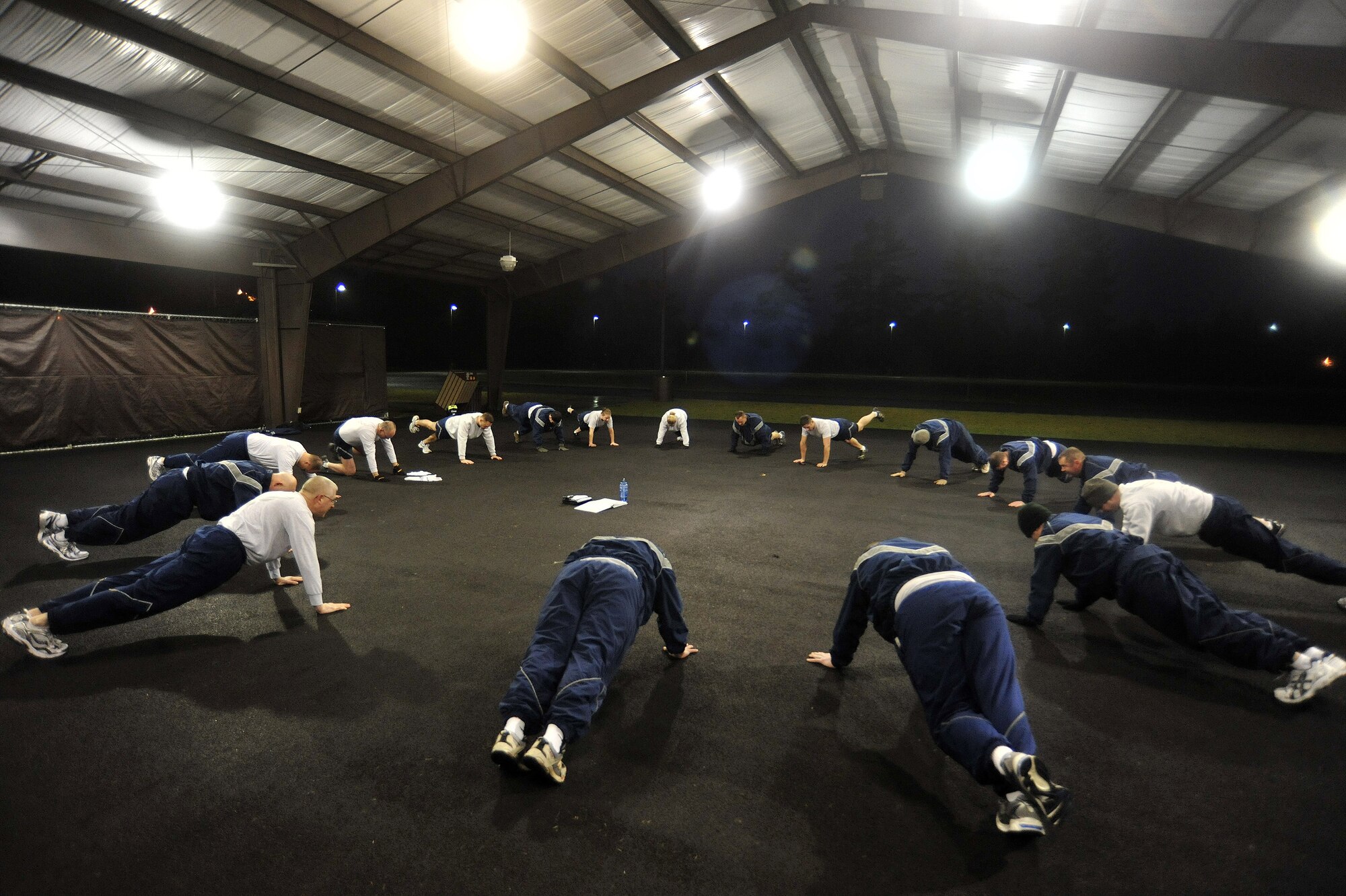 A group of Airmen conduct a morning physical training session with Lt. Gen. Robert Allardice, 18th Air Force commander, March 2, 2011, at Joint Base Lewis-McChord, Wash. The group performed callisthenic exercises, in addition to a team-building run. (U.S. Air Force photo/Airman 1st Class Leah Young)
