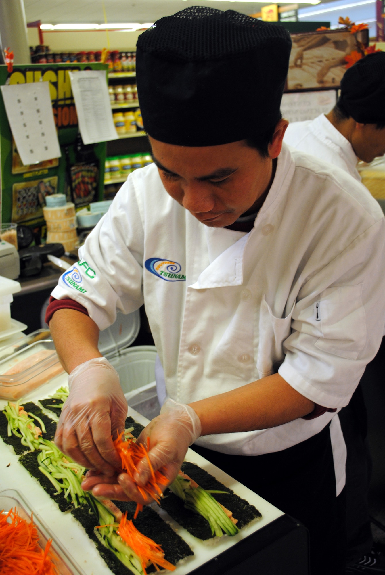 Steve Nyein, a sushi chef, places carrots inside sushi to add both color and texture to it.  Each sushi product the chefs make takes only a matter of minutes to complete. (U.S. Air Force photo/Airman Cortney Hansen)