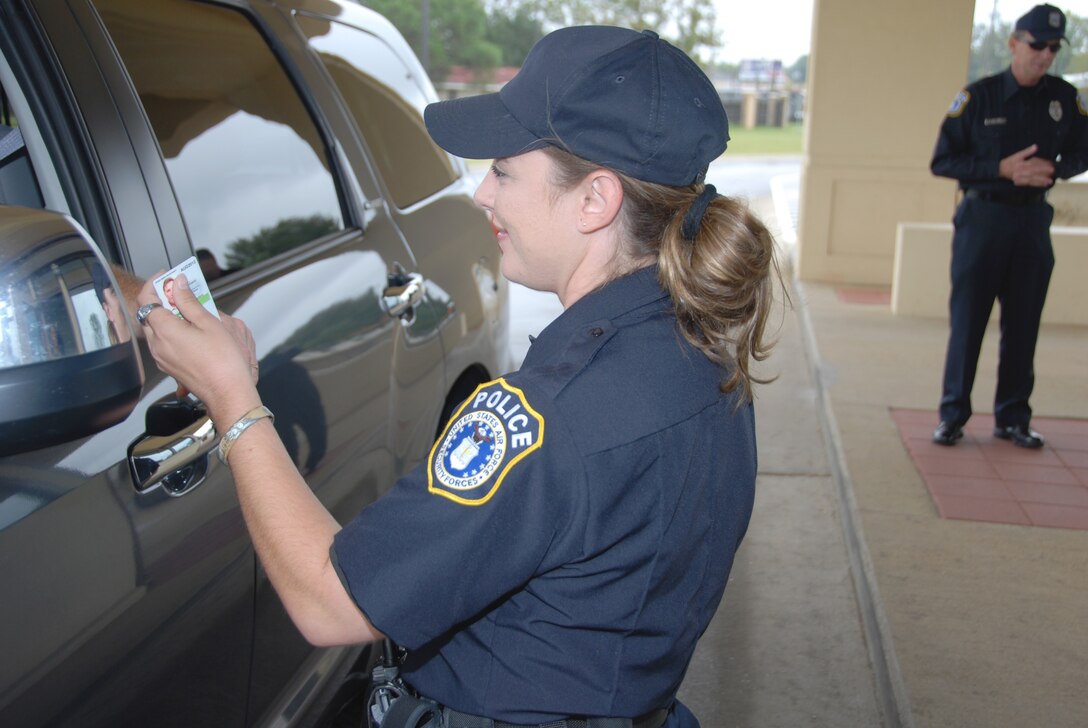 Department of the Air Force officer Monica Roberts examines the creditials of an individual at the Maxwell Boulevard gate. All who need access to the base are encouraged to register as soon as possible with the Defense Base Indentification System. Starting in July, gate guards will scan IDs to ensure authorized installation access. (Air Force photo/Wendy Simonds)